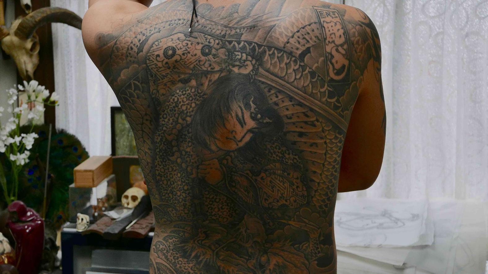 Νεαρό μέλος της Γιακούζα δείχνει το τατουάζ στην πλάτη του. 