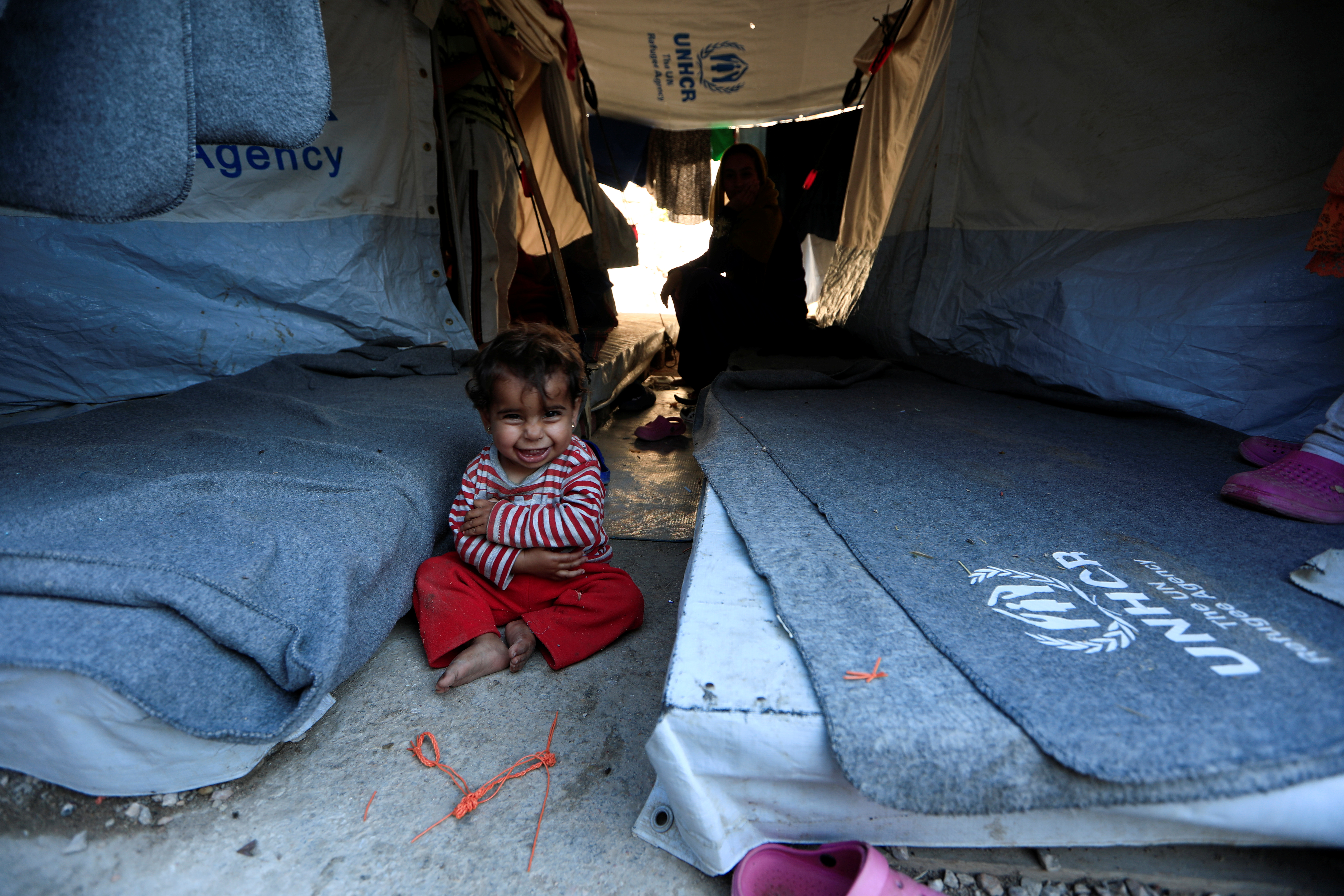 A one-year-old girl smiles as she sits with her mother at the Souda Refugee Camp in Chios island, Greece, June 10, 2017. (REUTERS/Zohra Bensemra)
