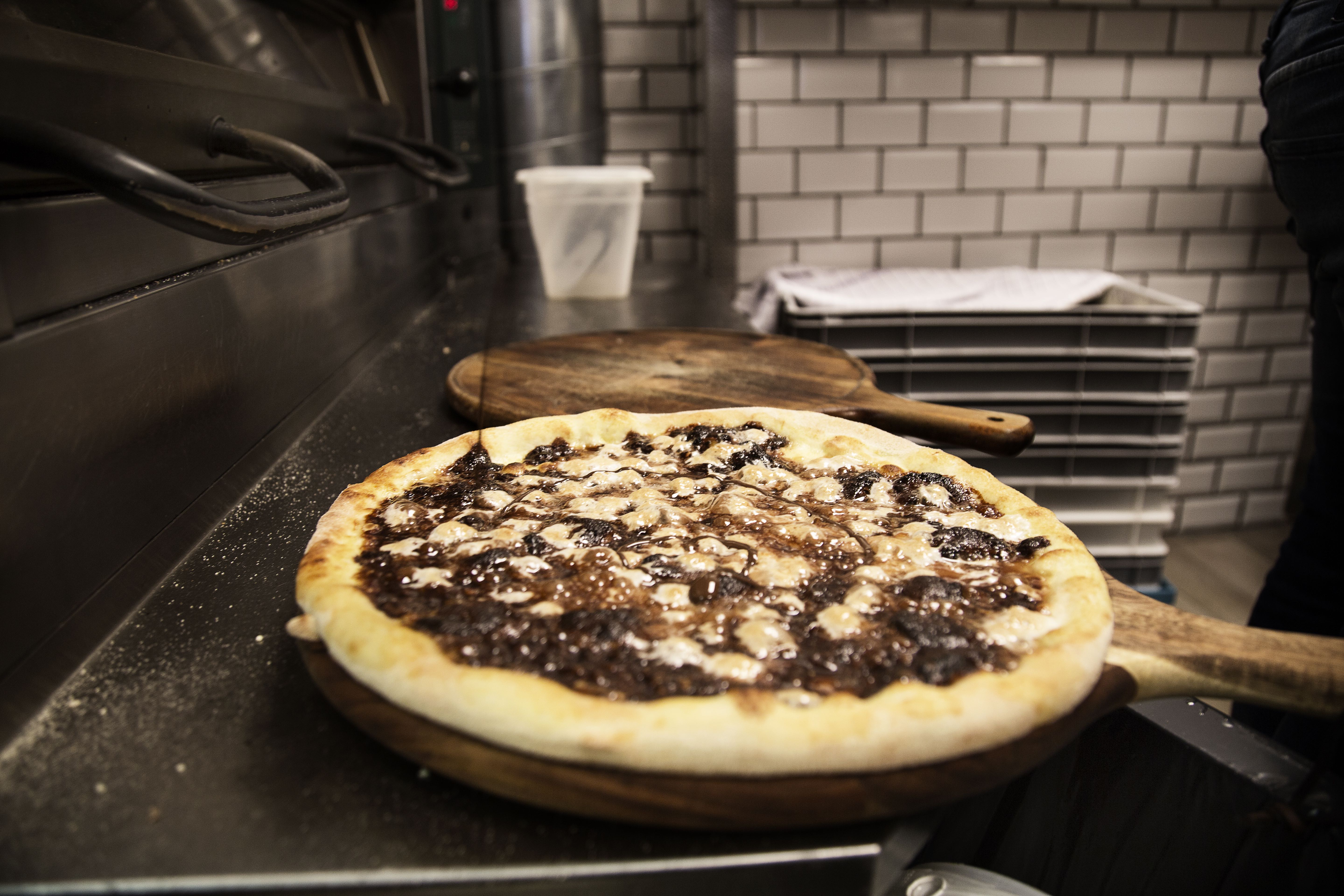 Den færdigbagte pizza får hældt chokoladesovs ud over sig.
