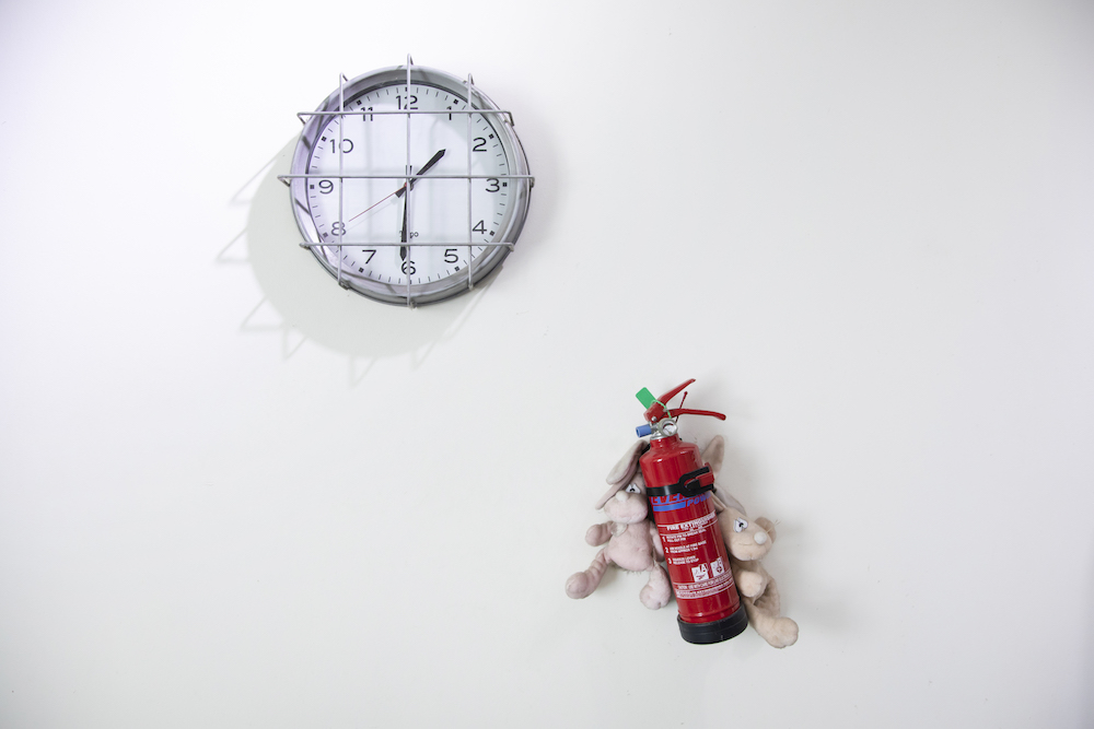Michells vergitterte Wanduhr und sein Feuerlöscher, den er mit Plüschtieren behängt hat