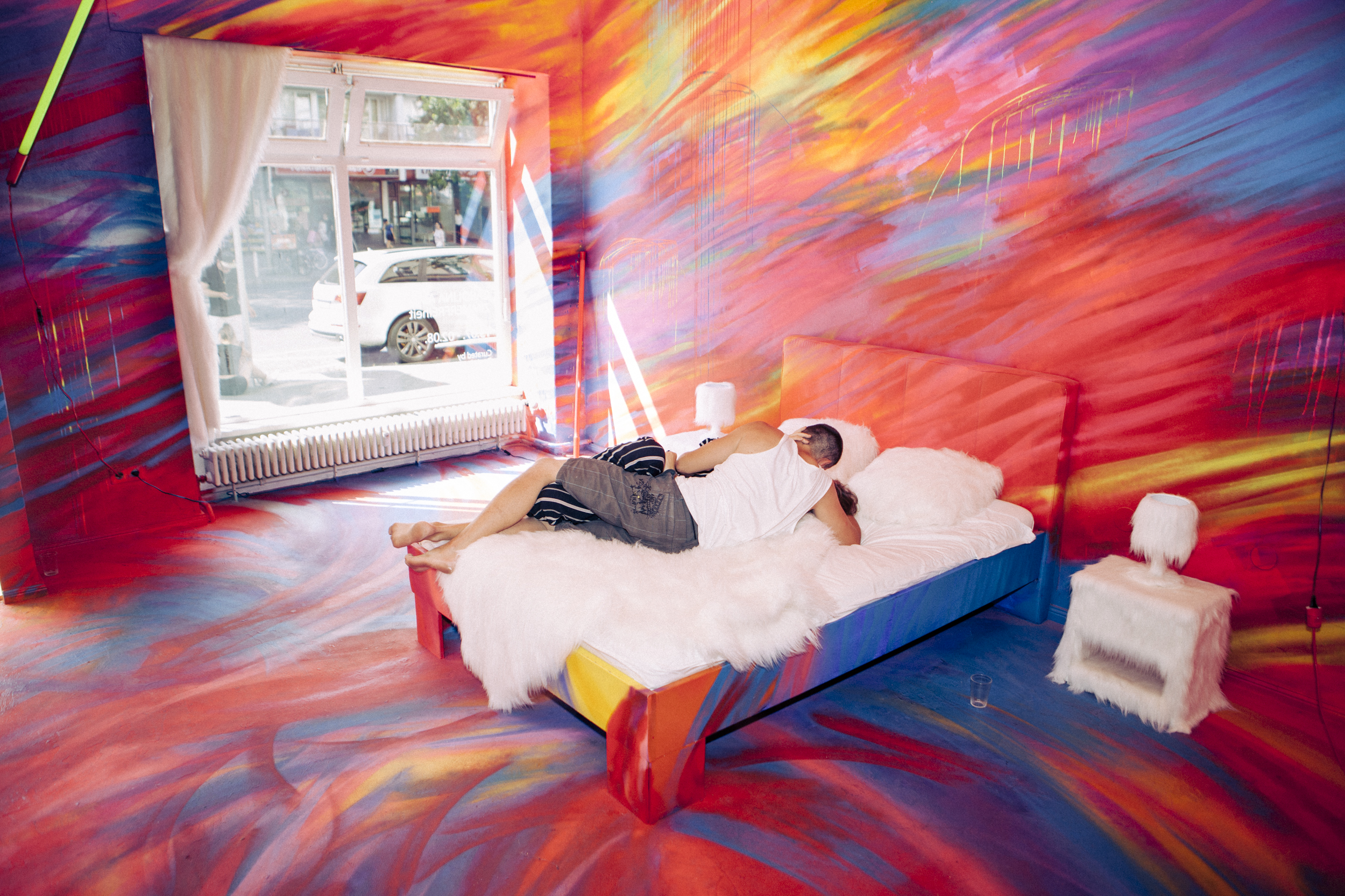 Ein Paar küsst sich auf einem Bett in einem bunt bemalten Raum