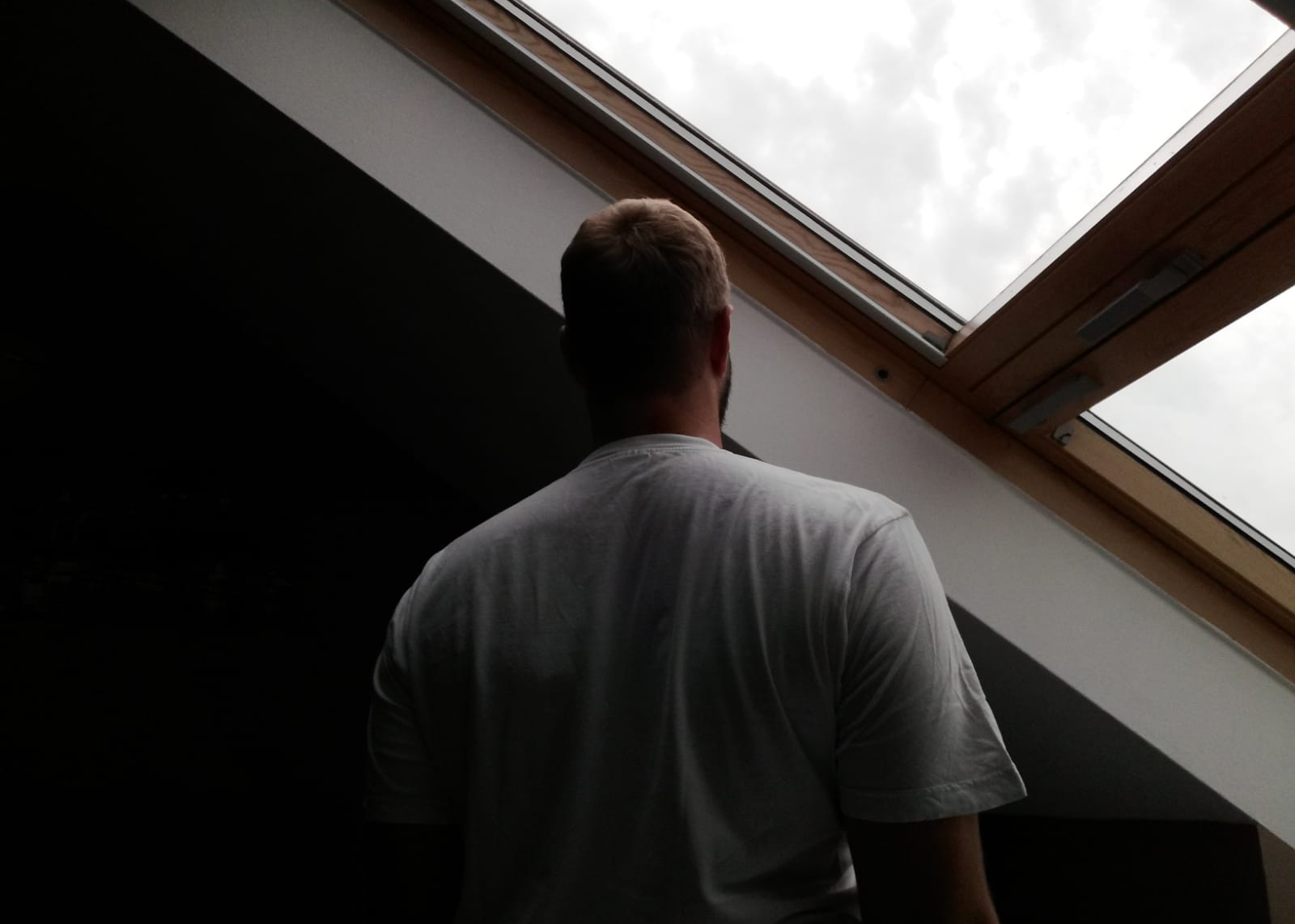 Ein Mann blickt aus einem Dachfenster, den Rücken zur Kamera