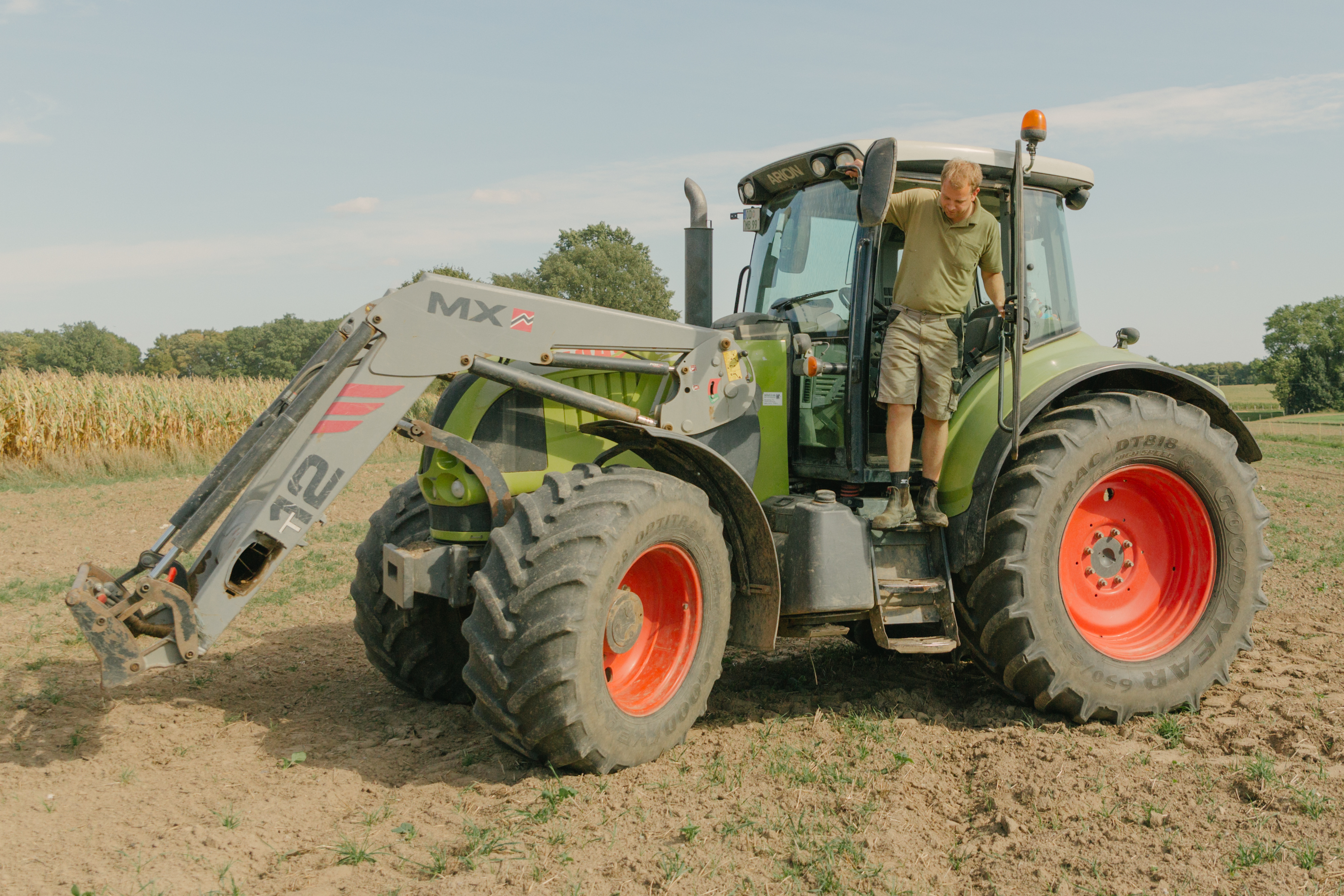 Der Bauer steht an der Fahrertür des Traktors