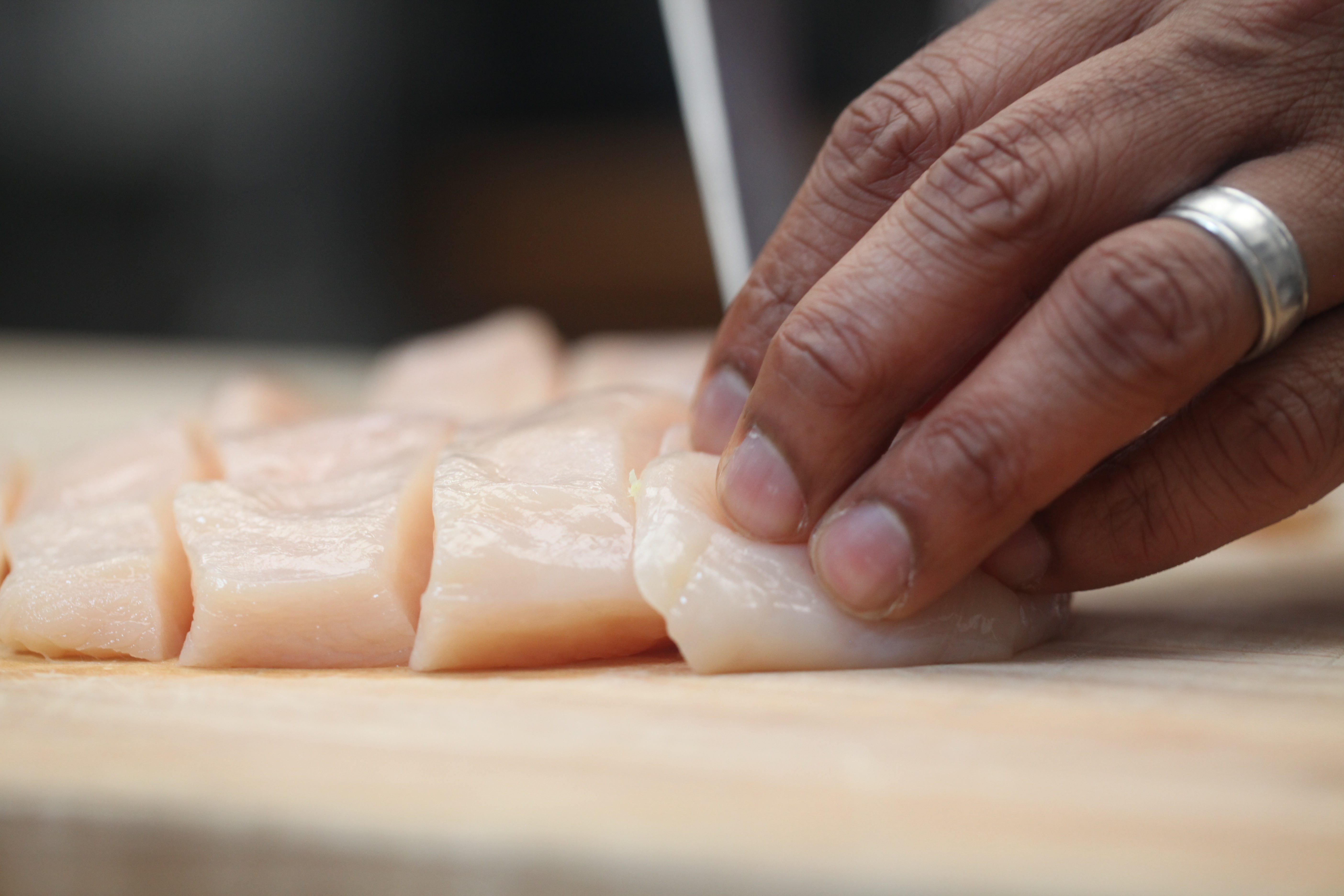 hands cutting raw chicken