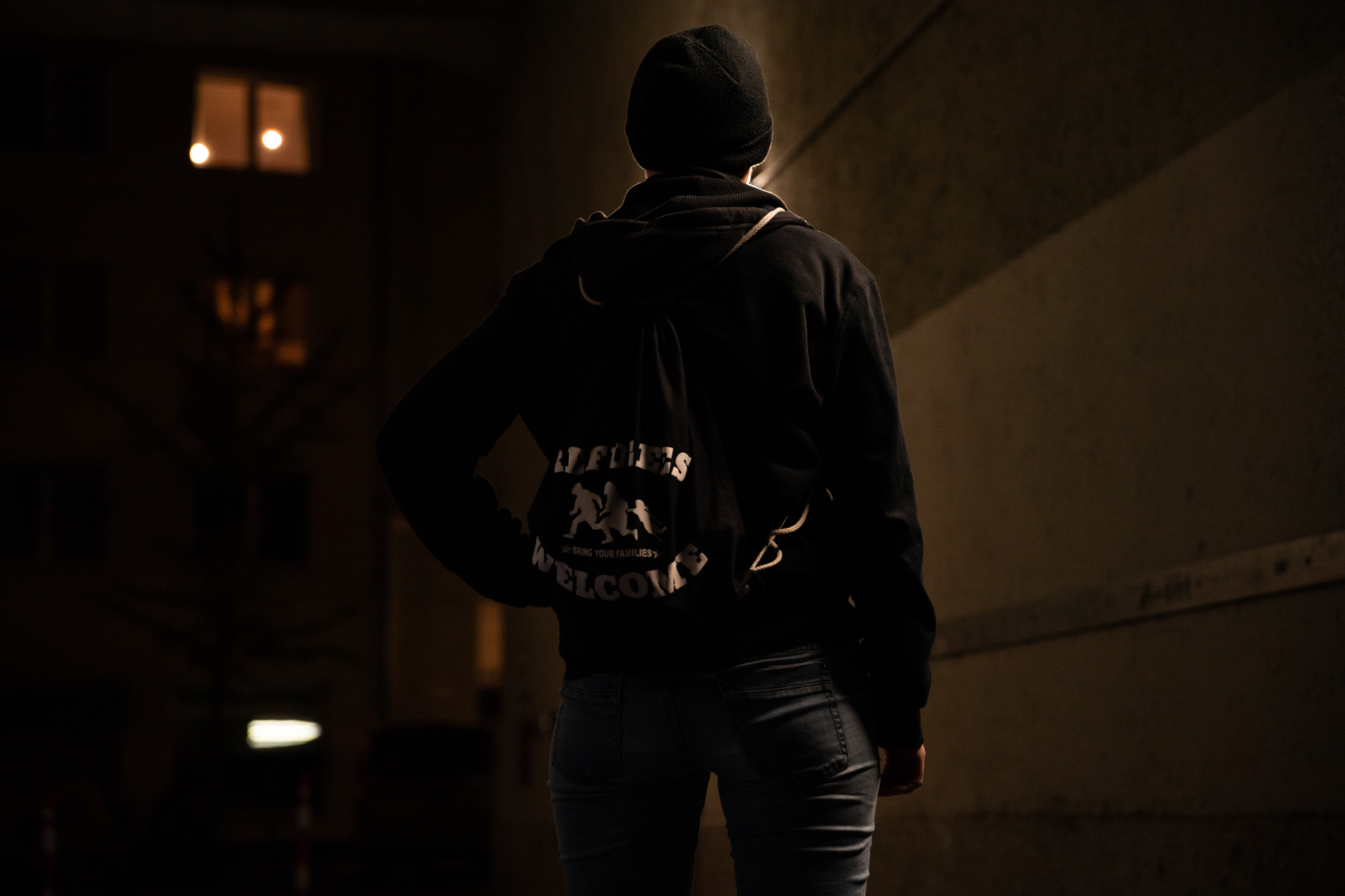 Person von hinten, sie trägt einen Rucksack auf dem steht Refugees Welcome