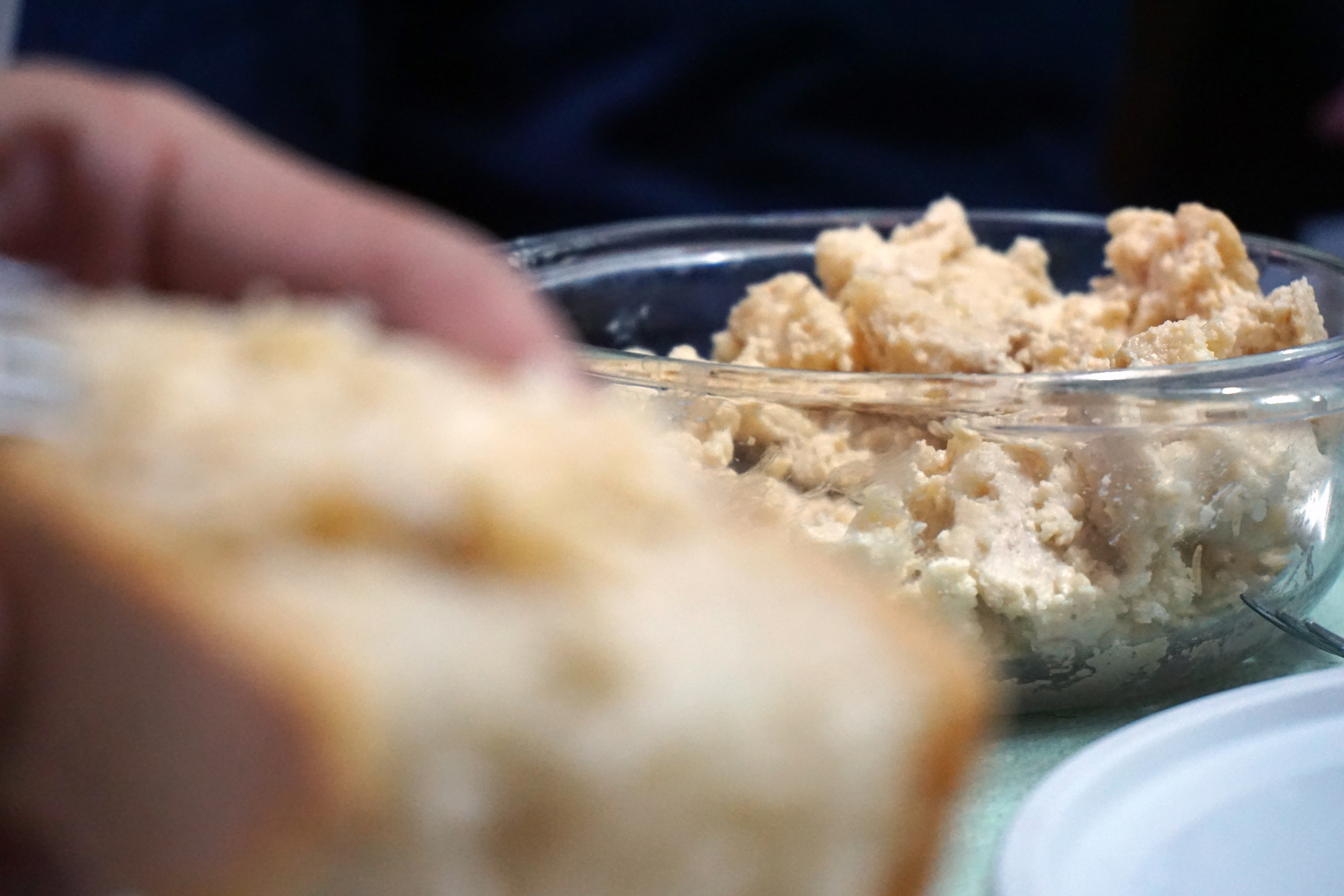 hand holding bread with cheese in the background