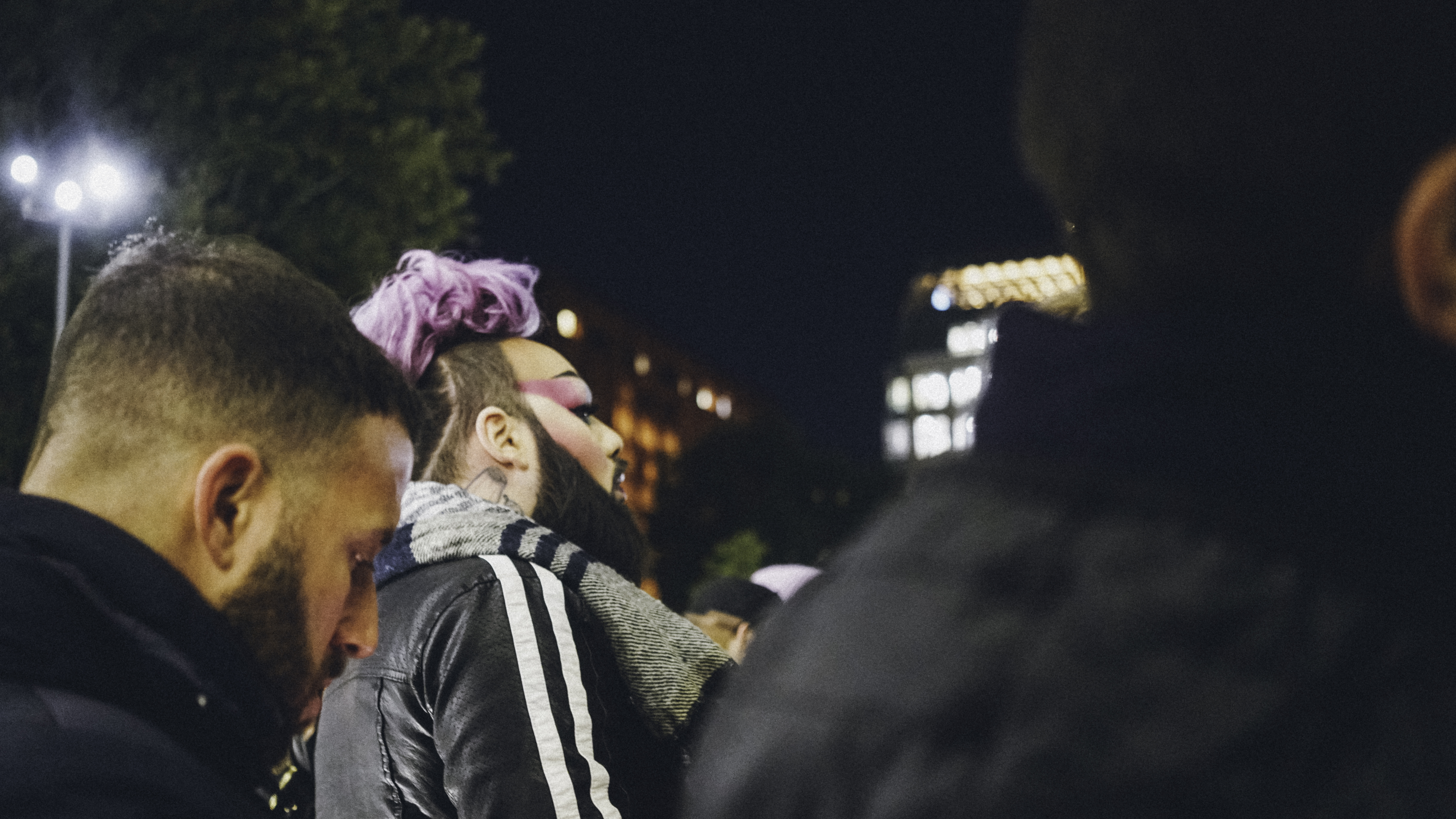 The side of someone's face, wearing lots of beautiful makeup, with brightly colored hair.