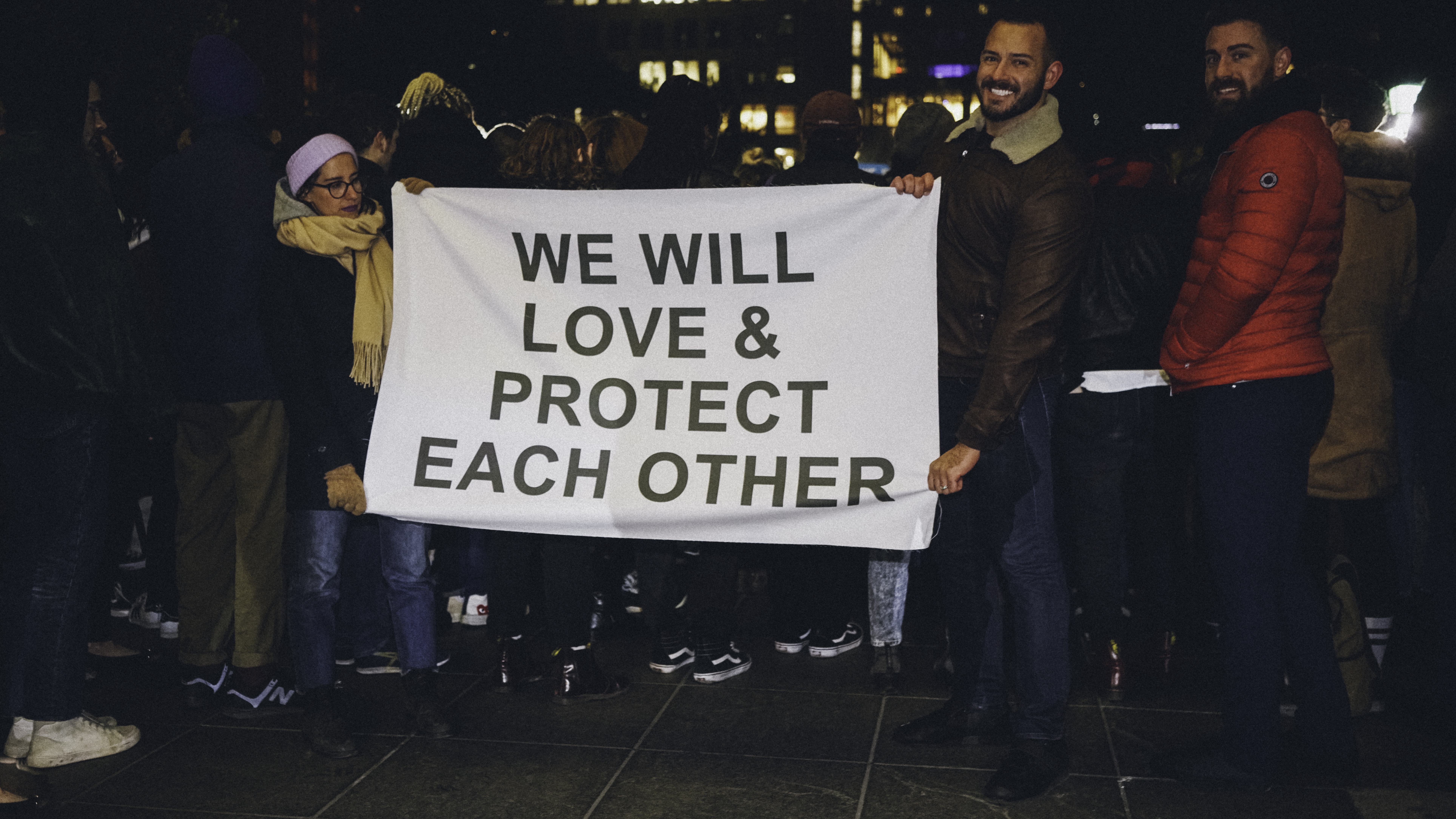 Two people holding a sign at a rally that reads,