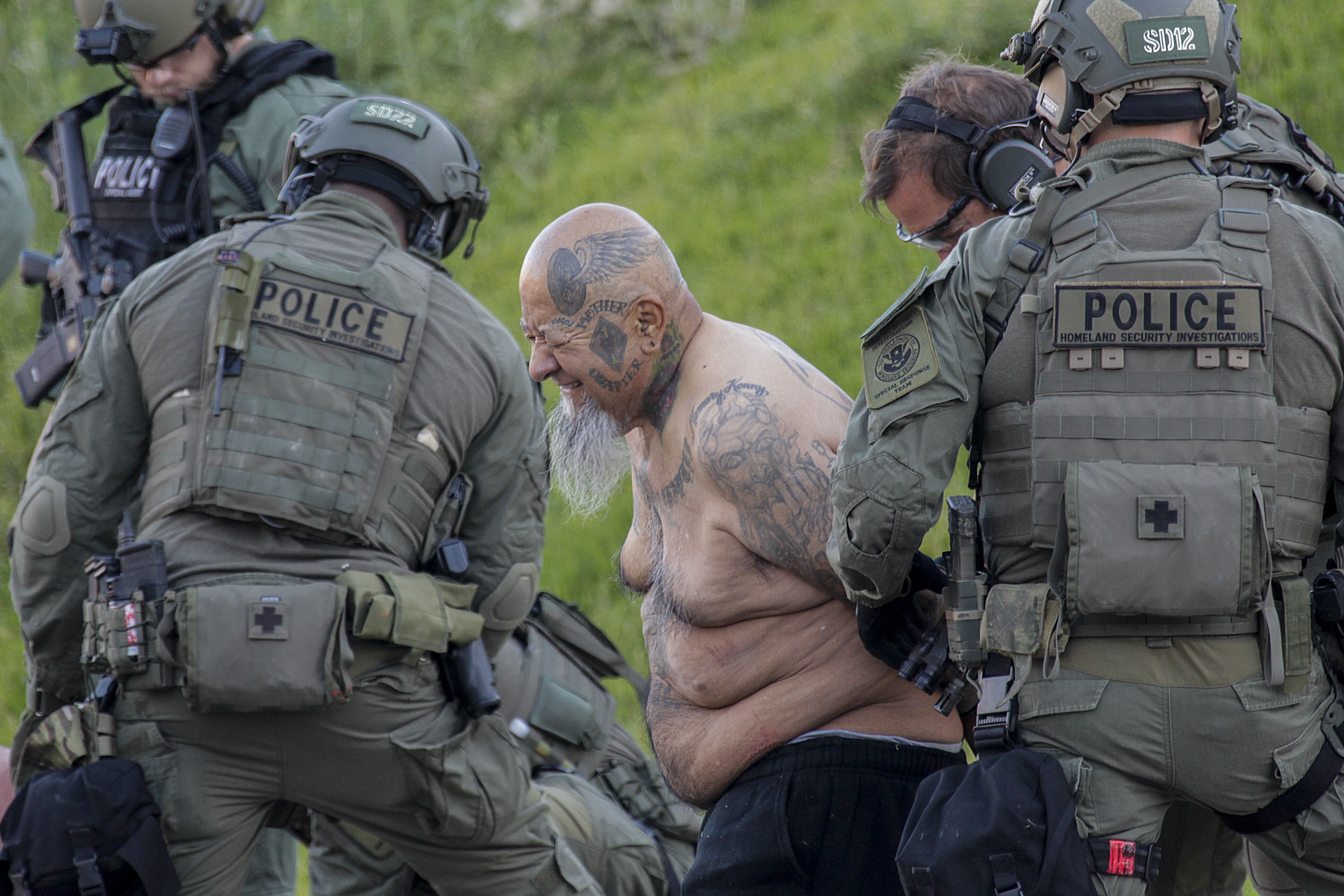 Federal agents arrest a person with Vagos motorcycle gang tattoos as a suspect in a 2011 murder of a rival gang leader. Early Friday morning June 16, 2017 federal agents detained many people after serving arrest and search warrants at home being operated as a rehab center, in Moreno Valley targeting a biker gang suspected of drug trafficking as well as murder.