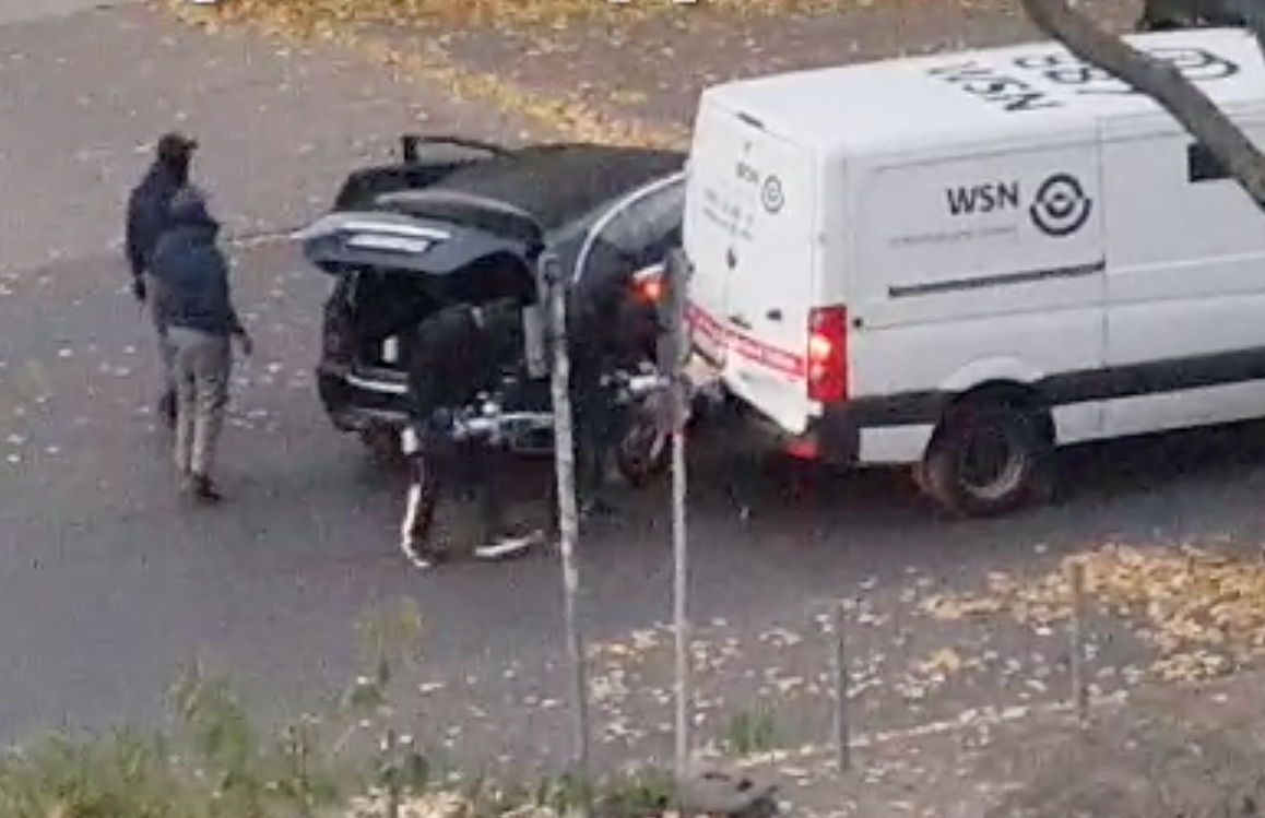 Zwei Räuber gehen mit Hydraulik-Spreizern auf die Heckklappe des Transporters zu.