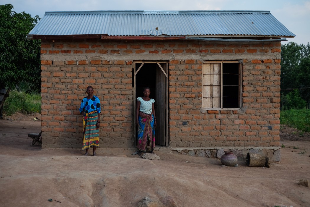 Les femmes en mariage nyumba ntobhu posent devant leur maison