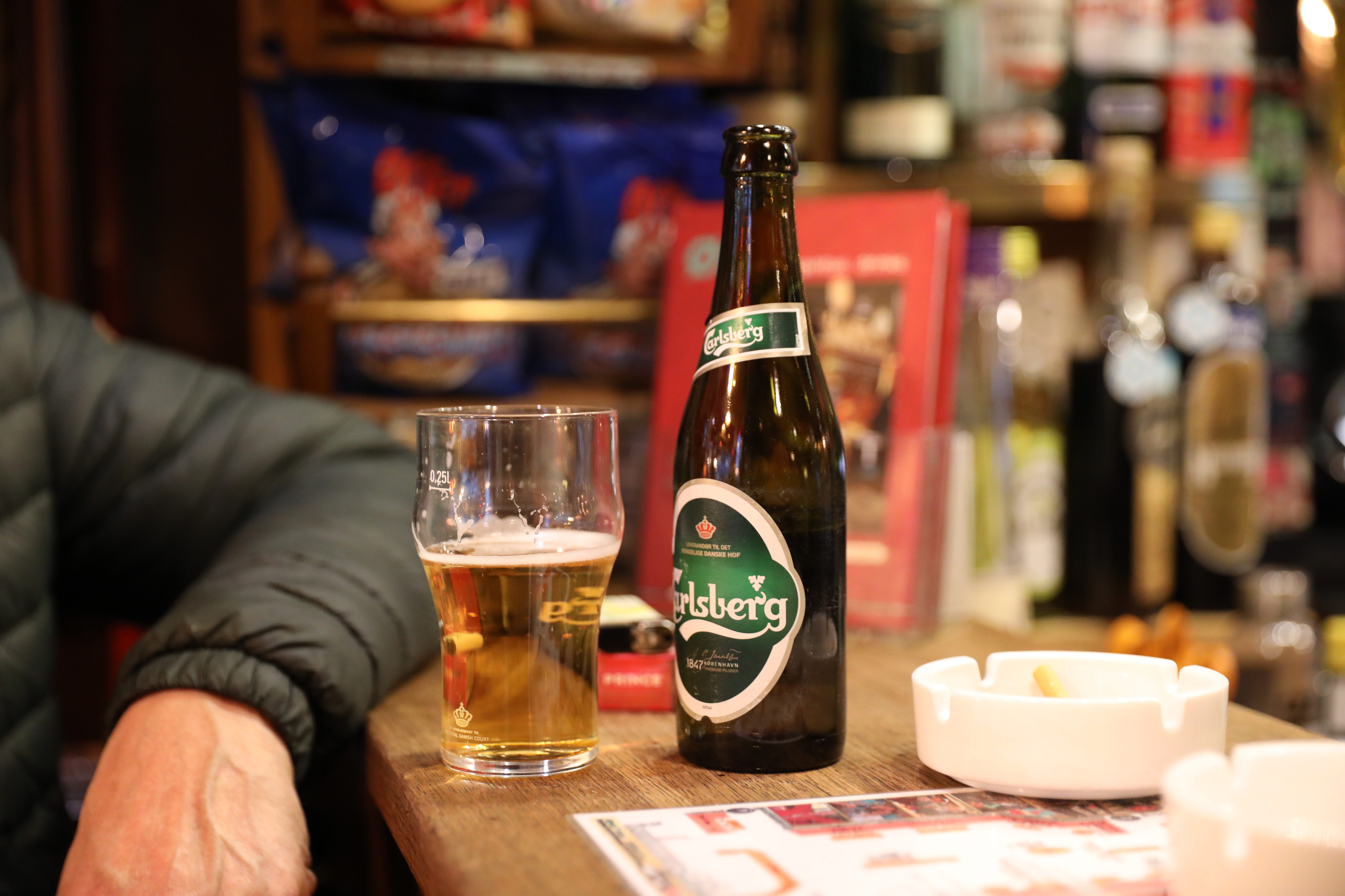 en ølflaske og et glas i baren på et værtshus.