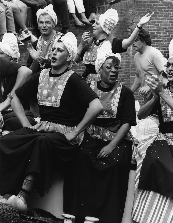 1541667781065-Groep-homomannen-en-twee-vrouwen-verkleed-meisjes-in-Nederlandse-klederdracht-op-klompen-tijdens-de-Gay-Pride-1996-canal-parade-in-Amsterdam-Gon-Buurman