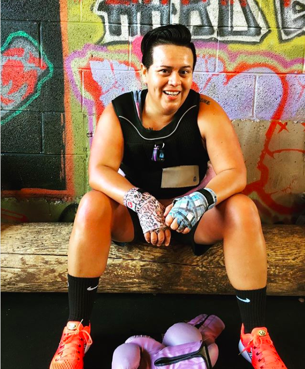 A person sits on a bench with boxing tape around their hands