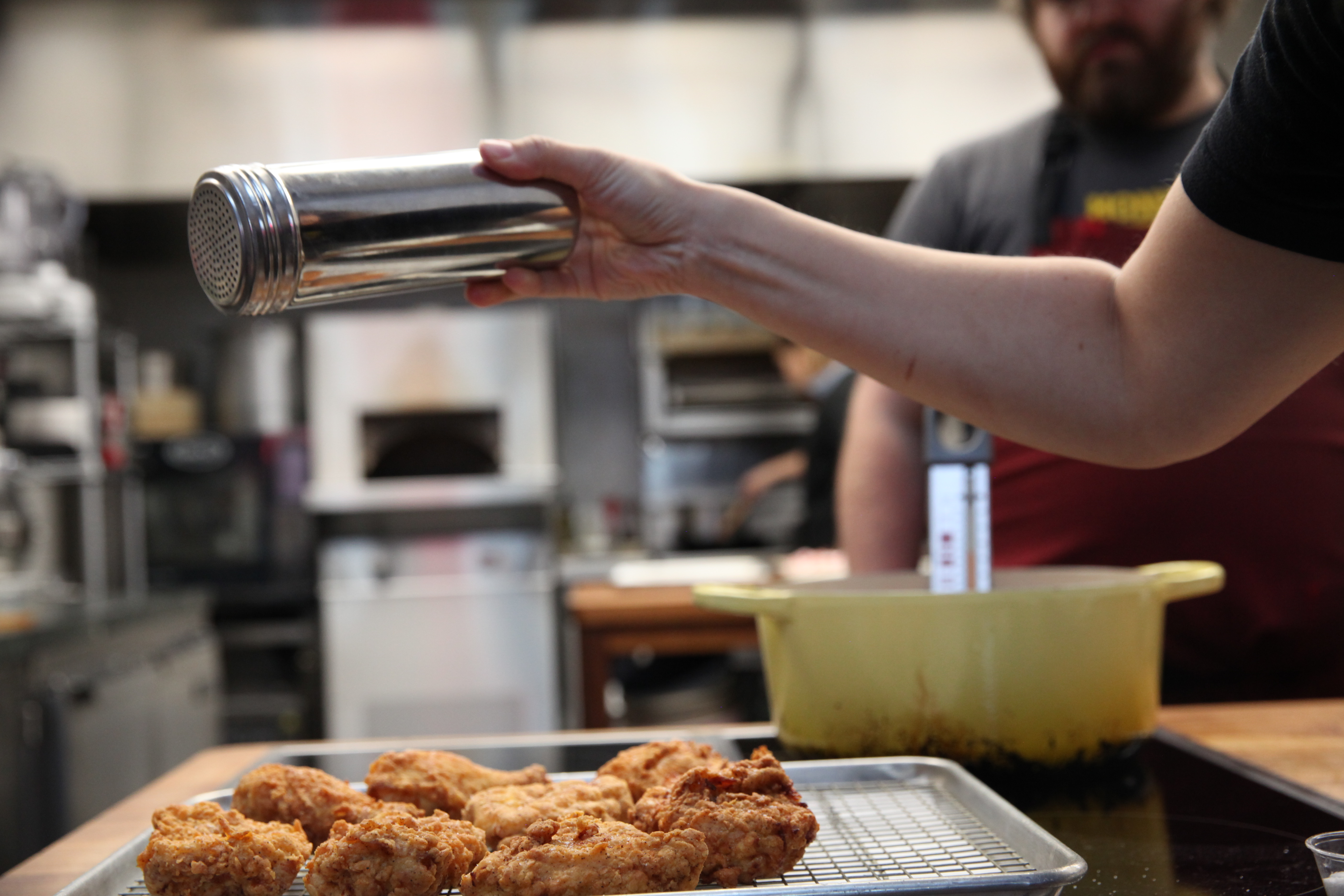 christine cikowski shaking smoked paprika onto fried chicken