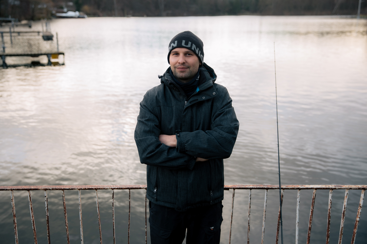 Ein Angler lehnt an ein Geländer am See in Müggelheim