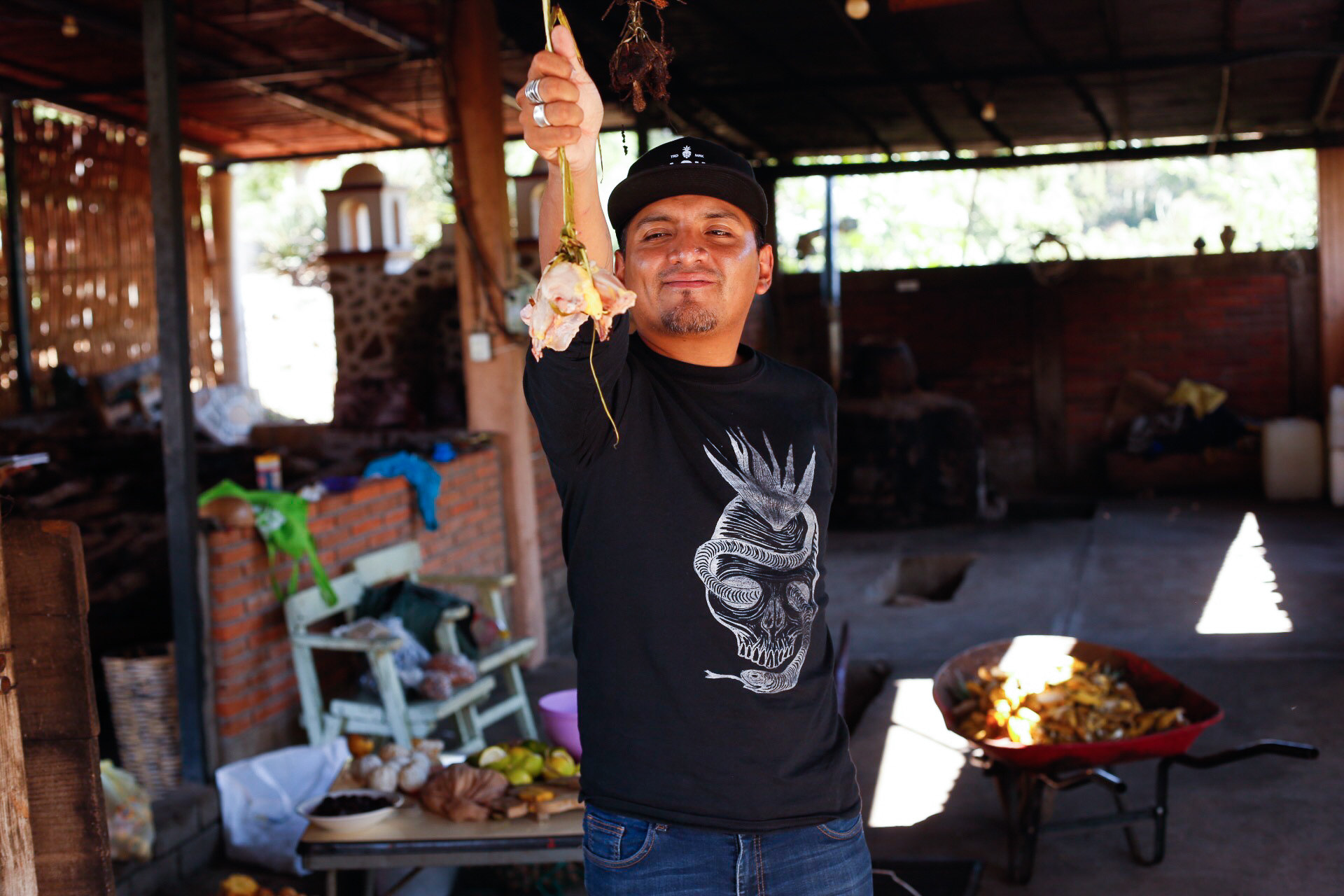 Alonso holding a raw chicken breast, which will soon be used in pechuga mezcal.