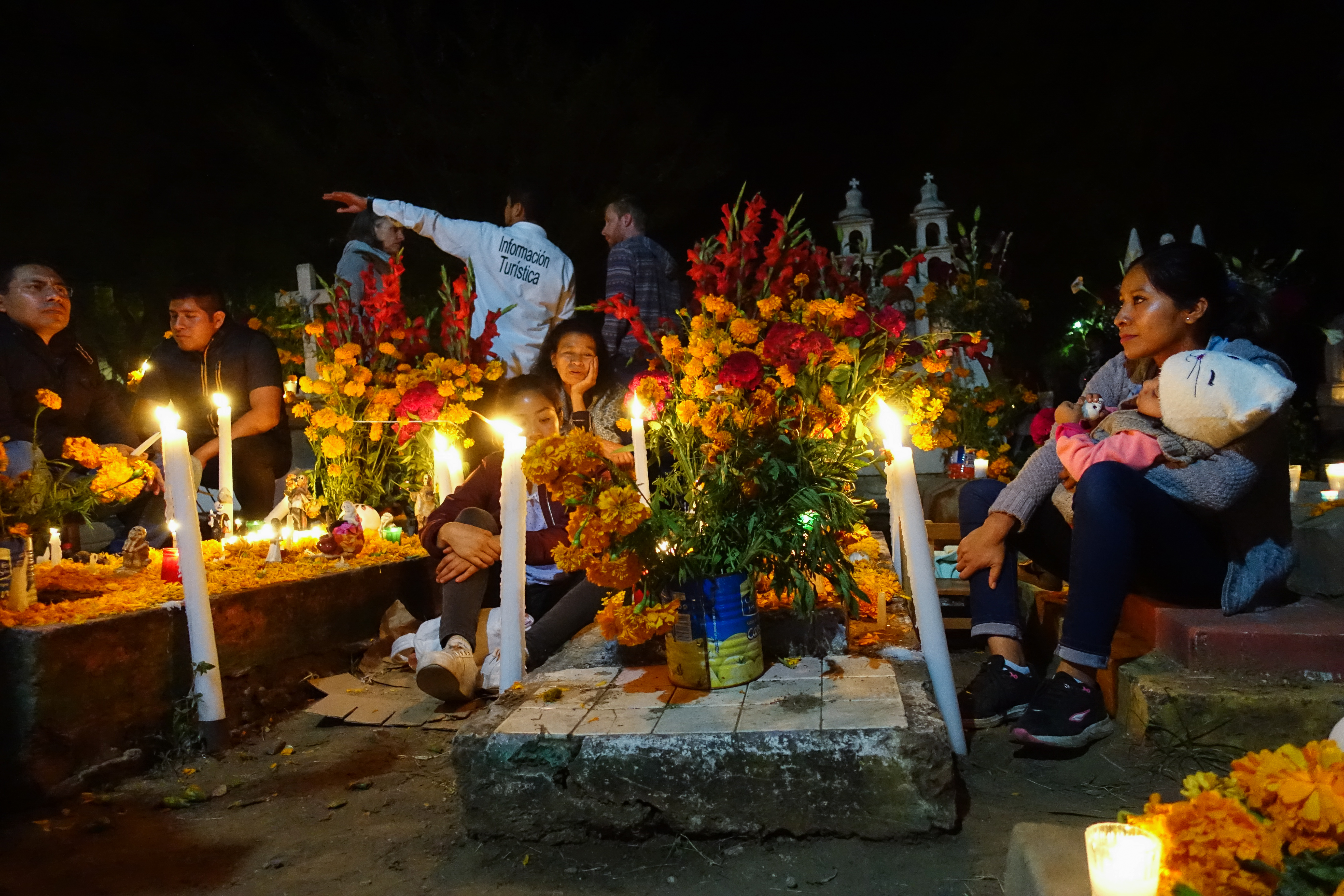 Eine Familie sitzt am geschmückten Grab ihrer Verwandten