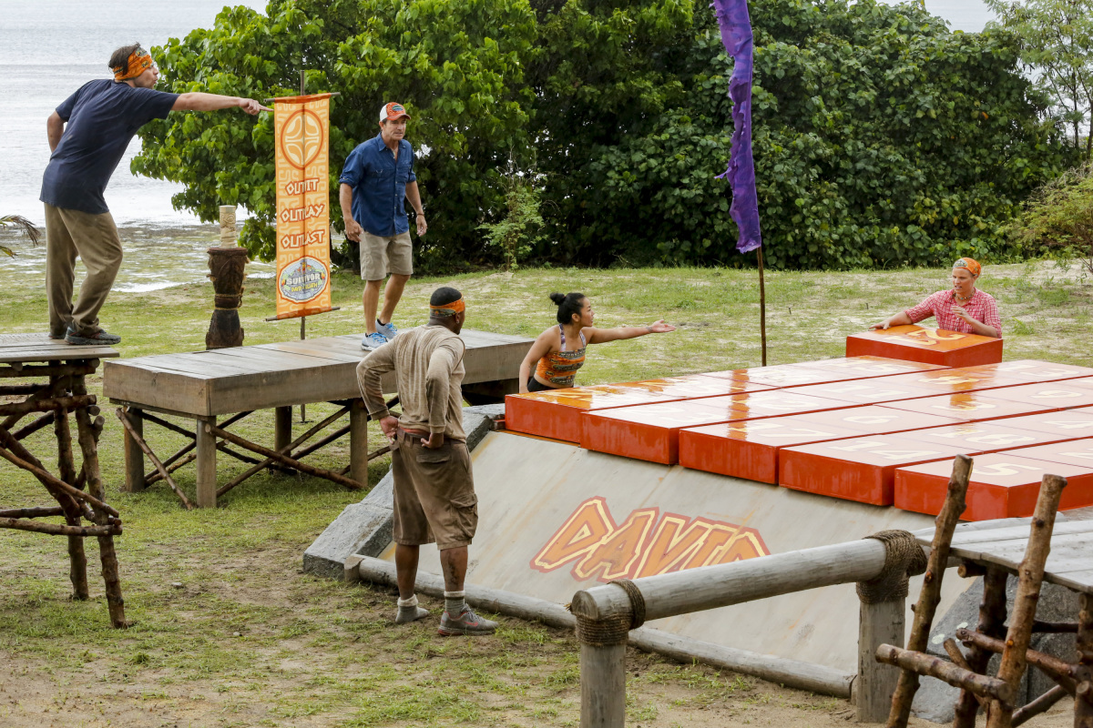 Survivor contestant Christian directs teammates to complete a puzzle.