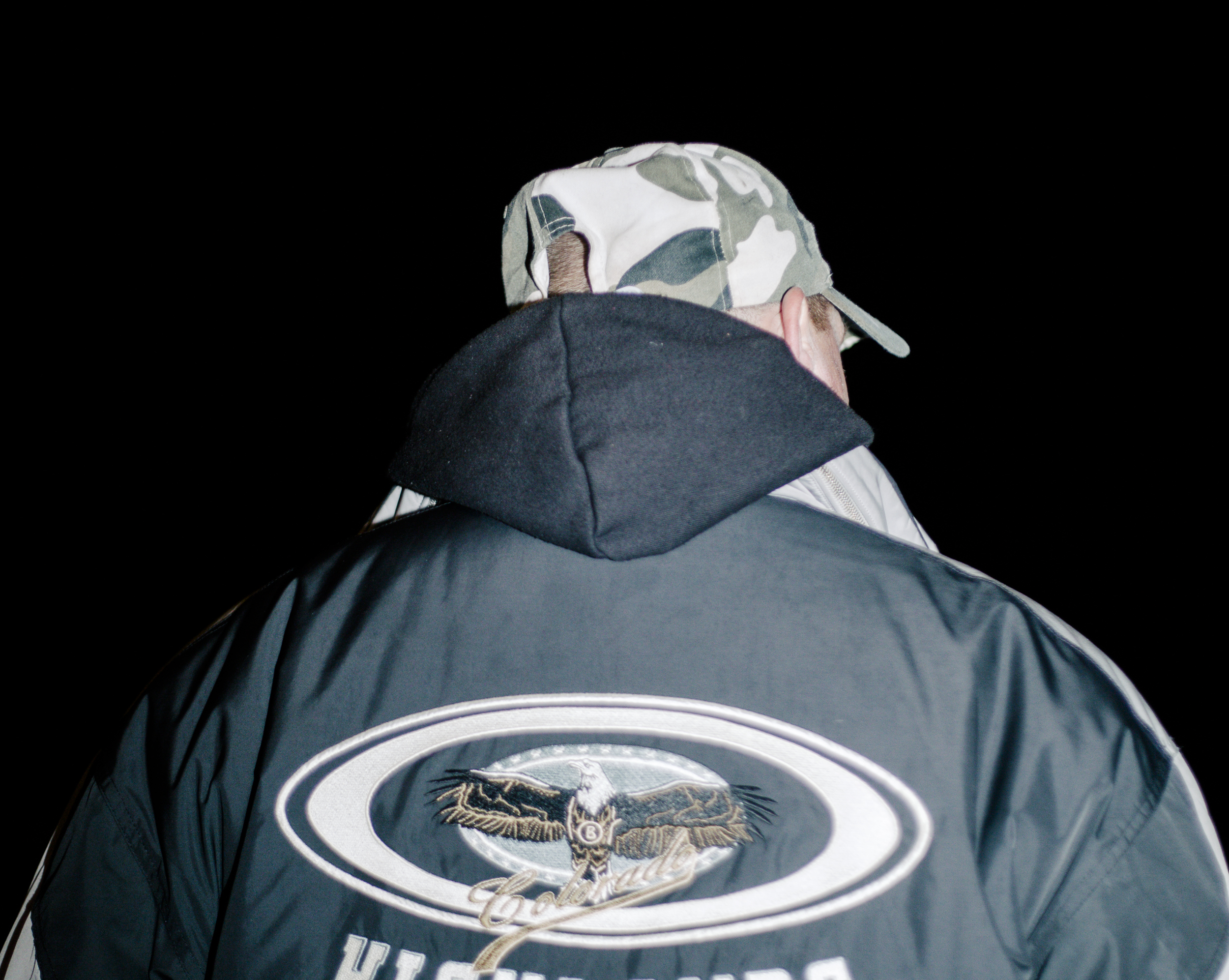rücken eines obdachlosen mannes, er trägt einen anorak mit einem adler drauf