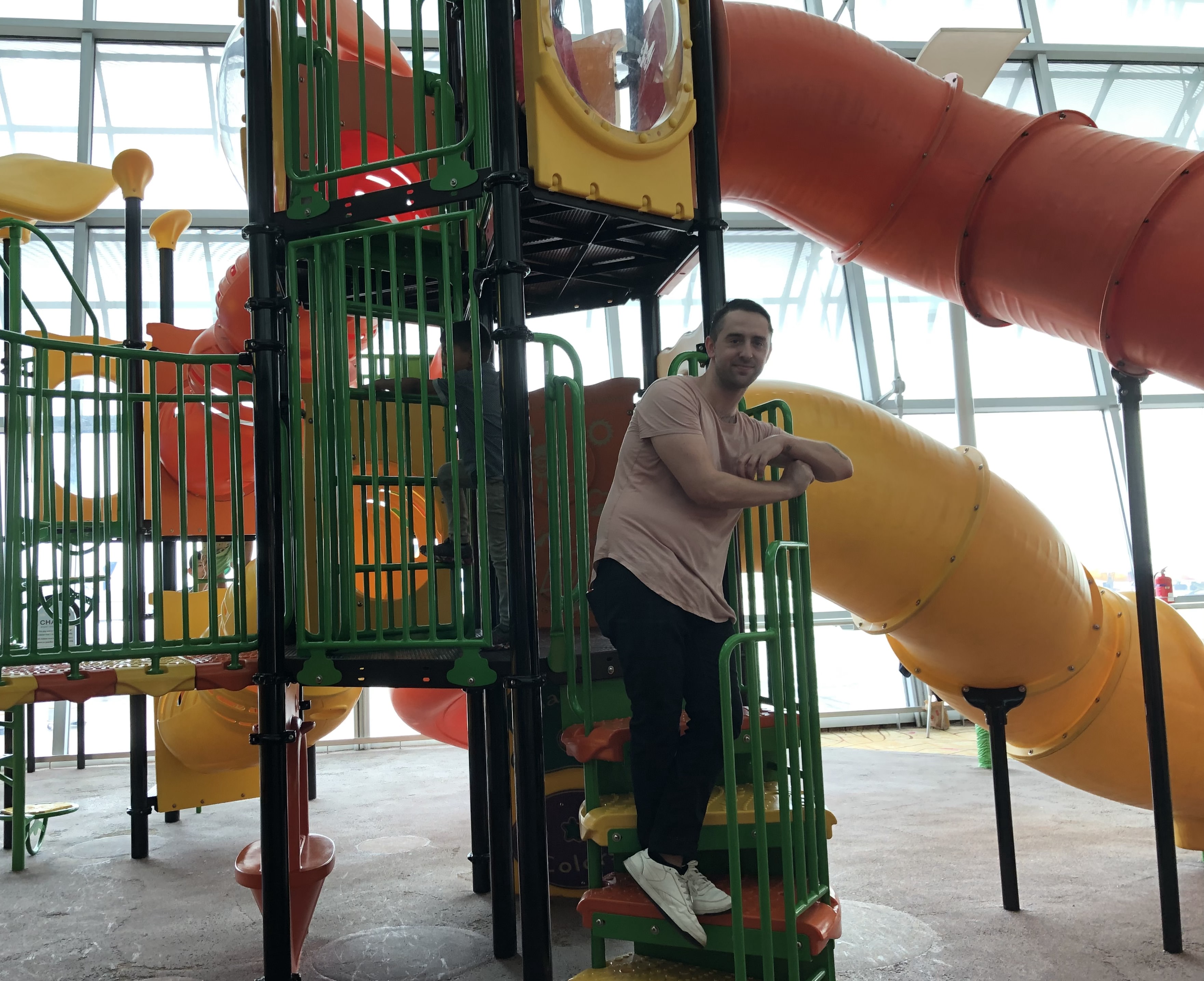 a man stands on a playground jungle gym that is inside an airport