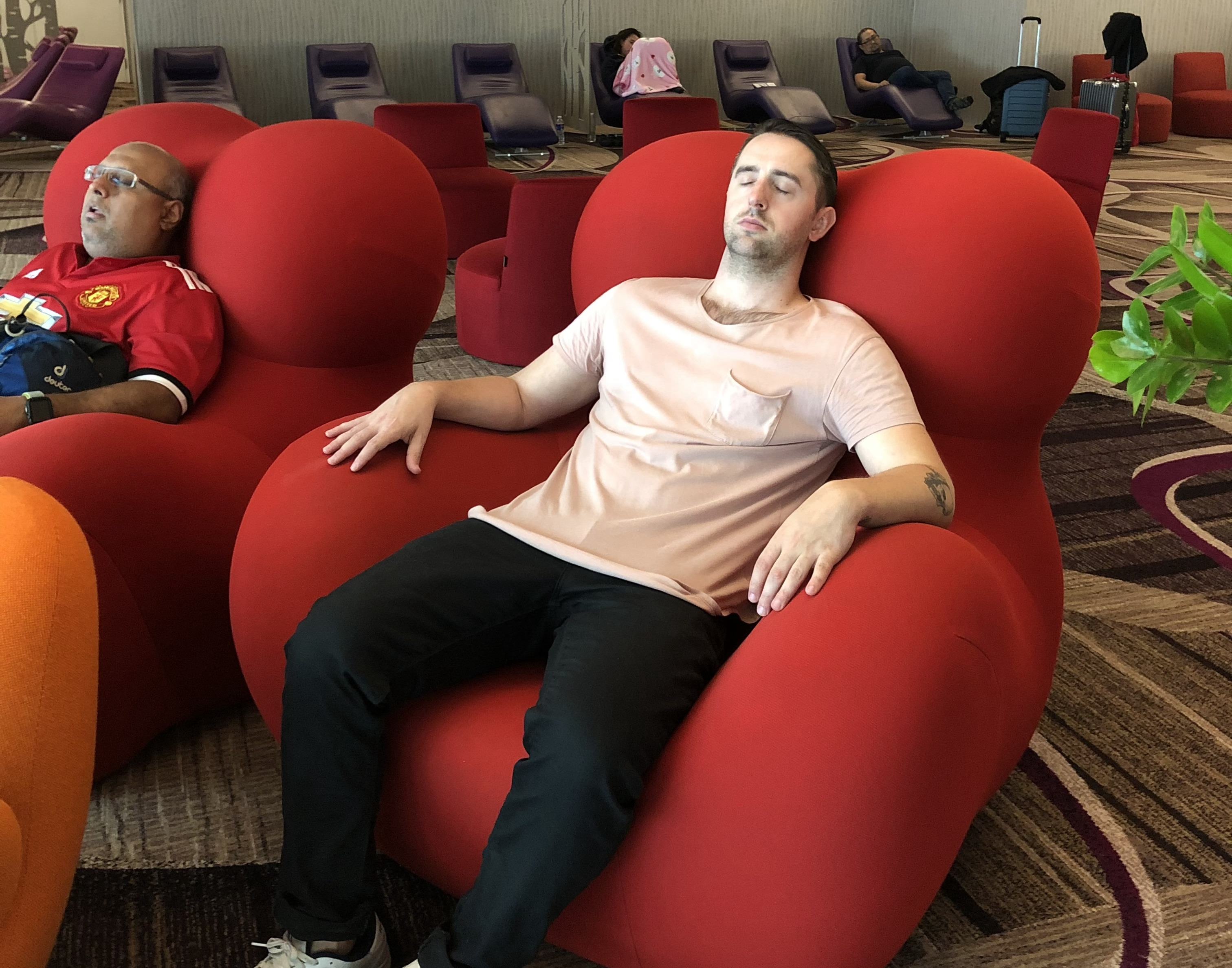 a man sleeps in a large red chair