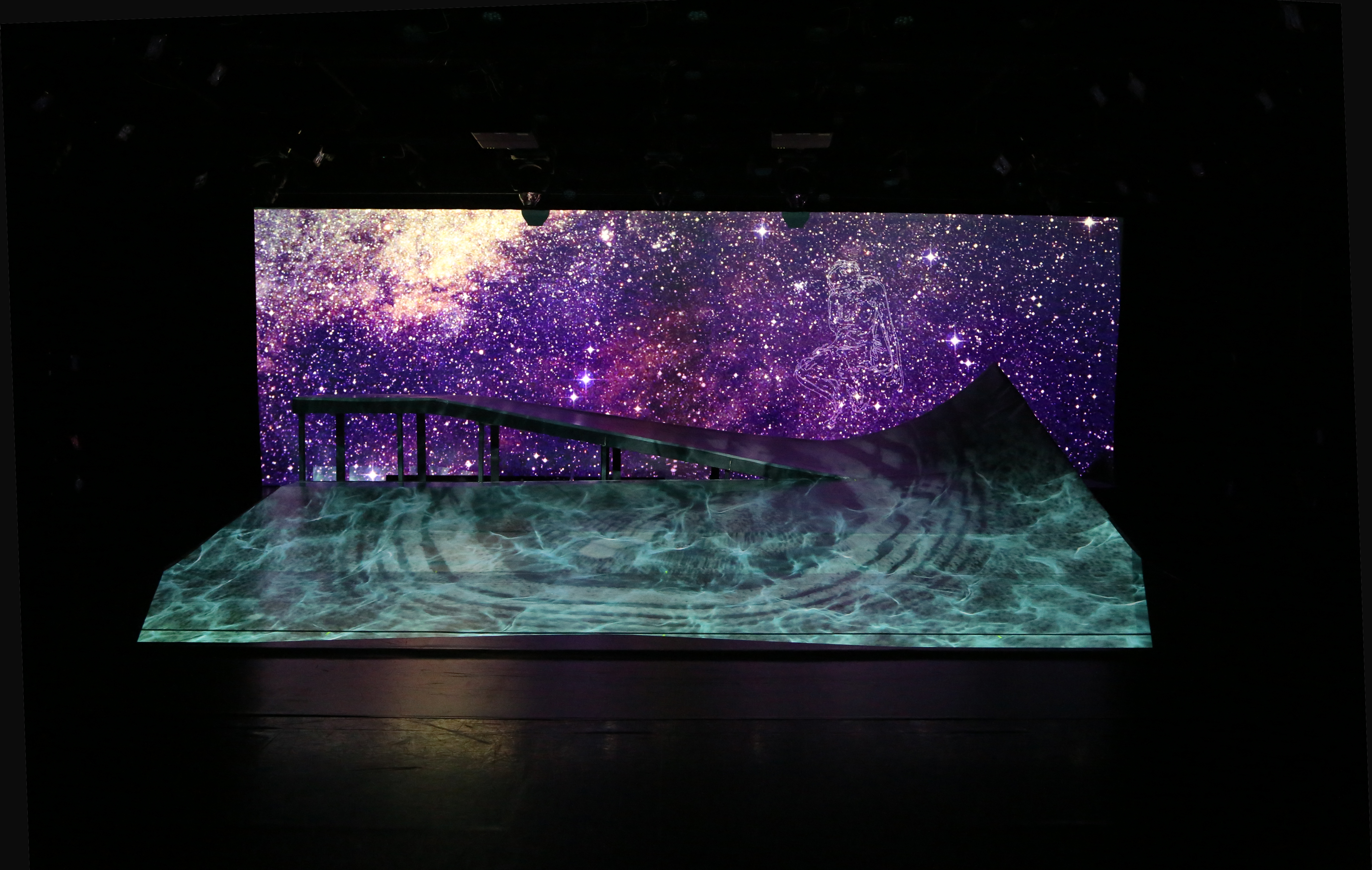 The ramp, spanning 24 by 15 feet across the stage, with the righthand peak reaching six feet. Throughout DESCENT it is illuminated with art, landscapes and stars projected by Michael Maag.