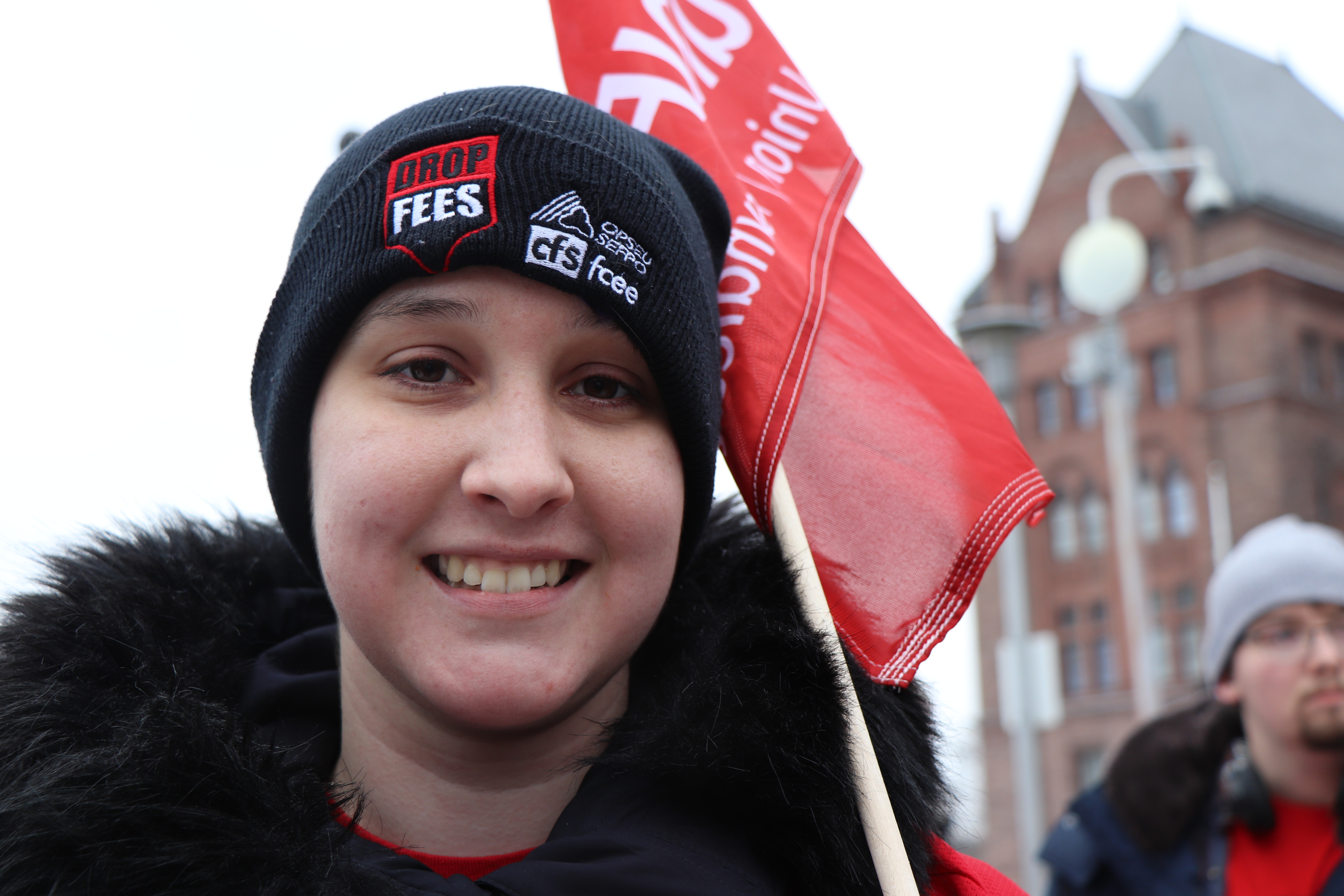 Kaitlyn Teller, a support staff worker at UOIT, waves a banner during the protest against tuition cuts and ancillary fee changes on Jan. 19 at Queen’s Park. Photo: Emma Sandri 