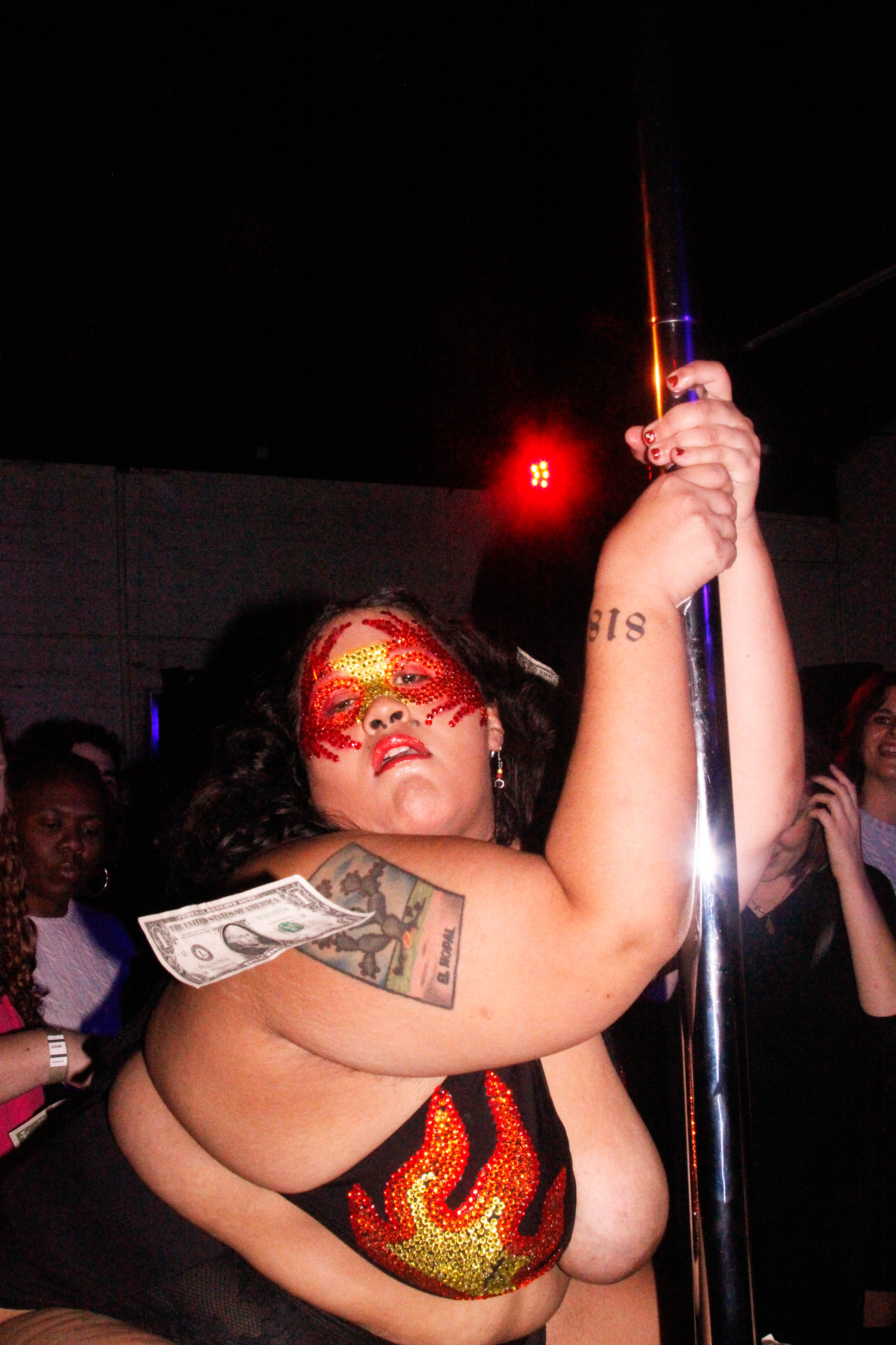 A stripper in a msk, clinging on to a pole
