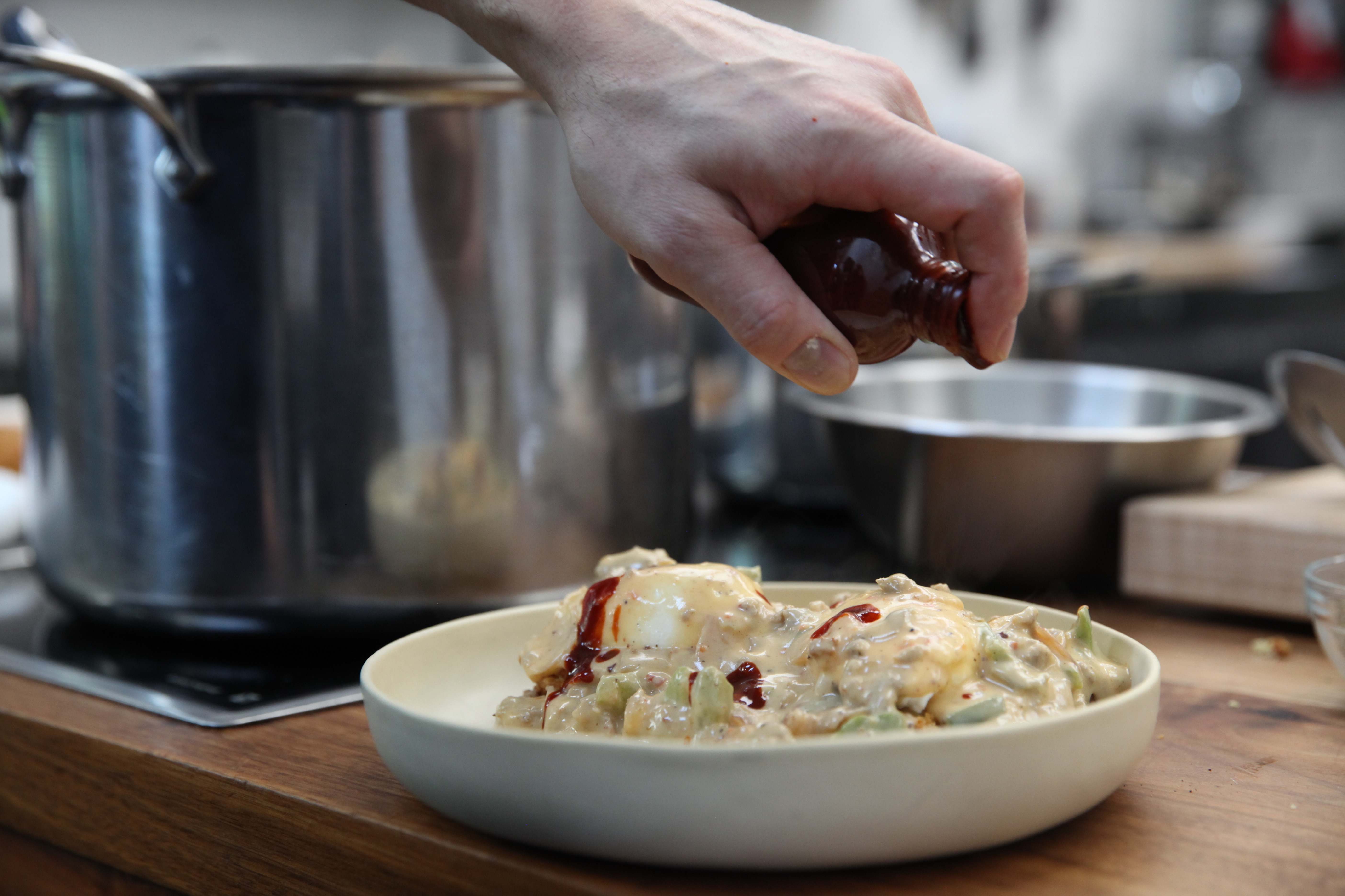 chef jaime young topping sausage and gravy biscuits with hot sauce