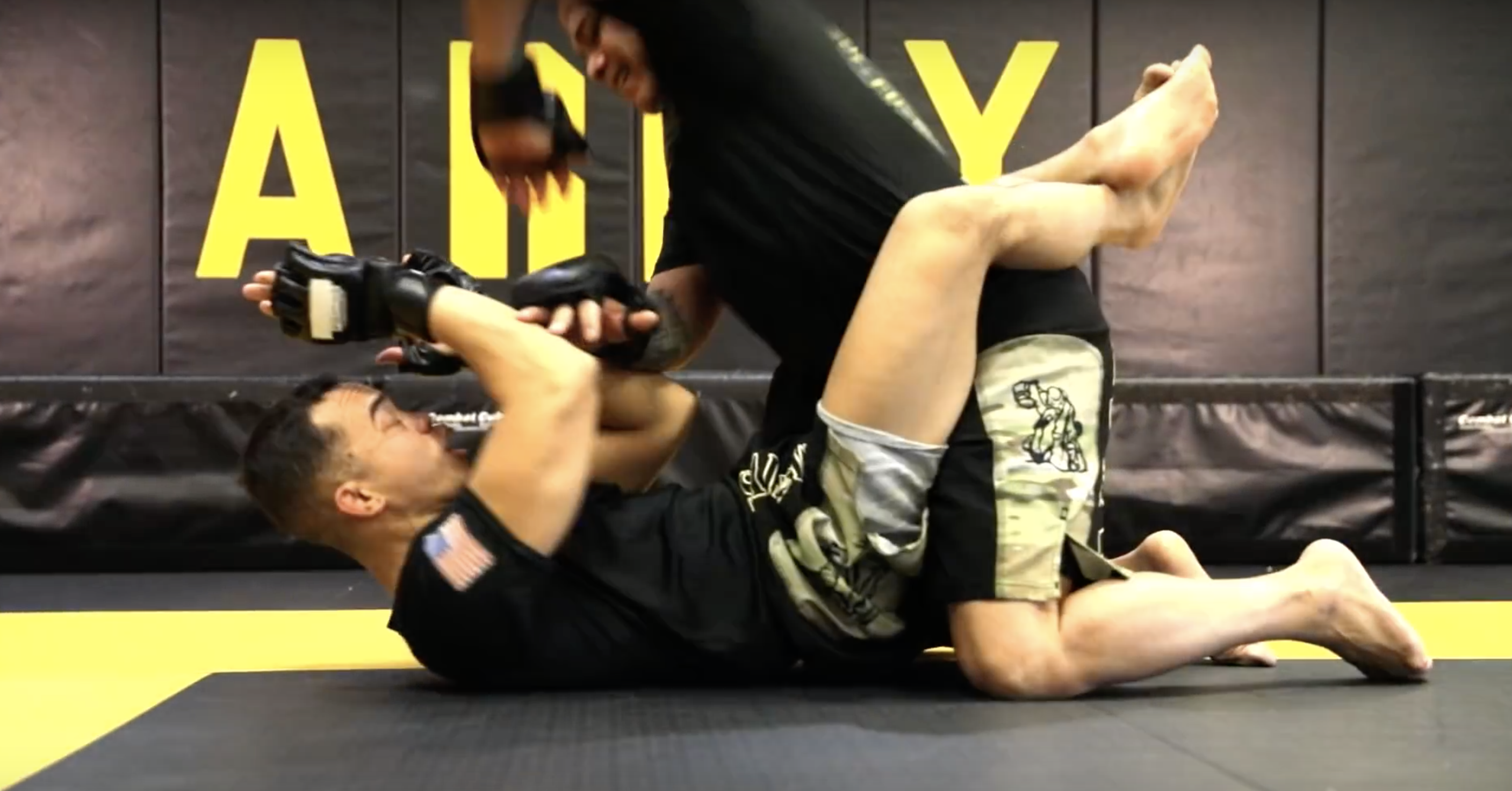 Two MMA fighters grappling on the mat