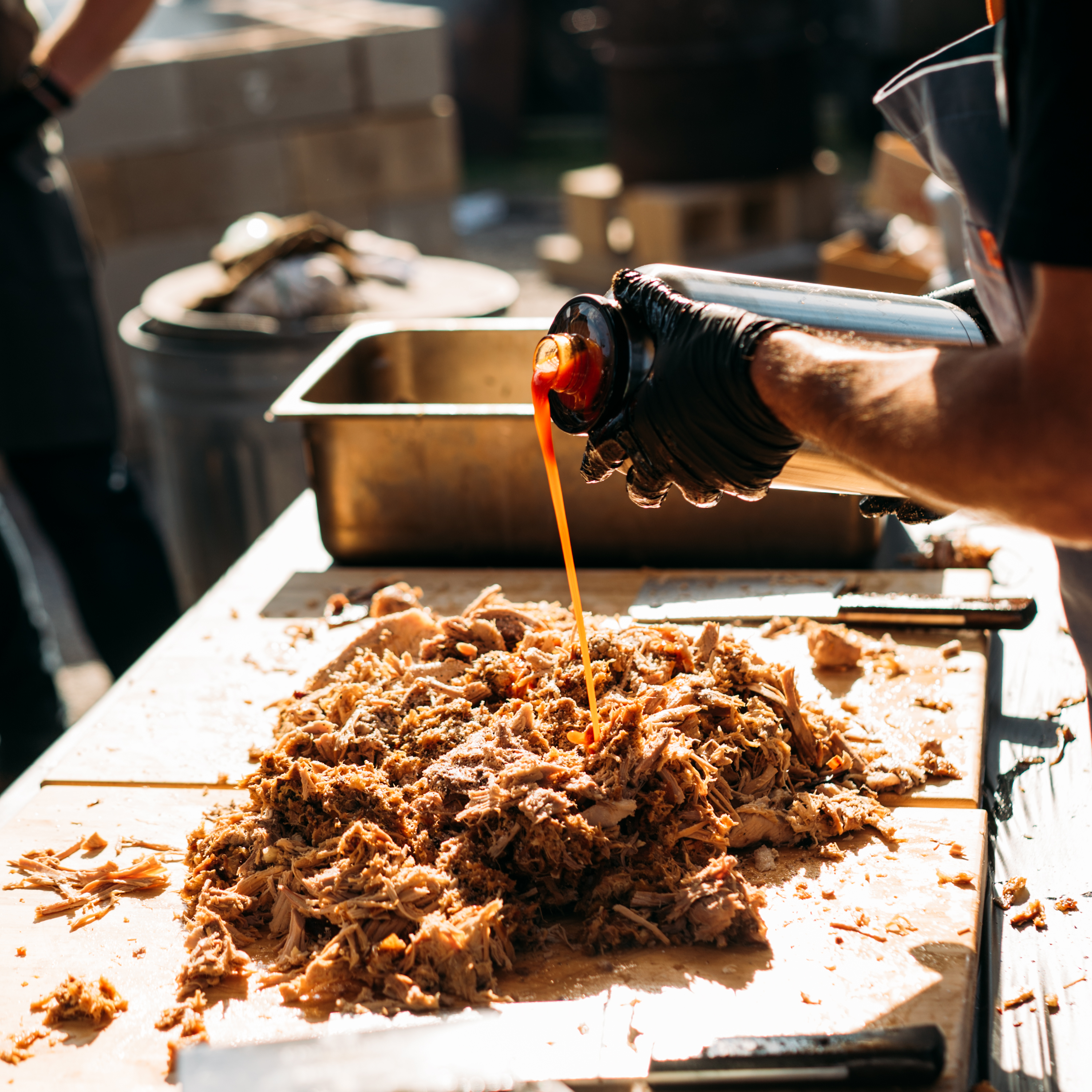 barbecue sauce being poured onto chopped meat at hot luck festival
