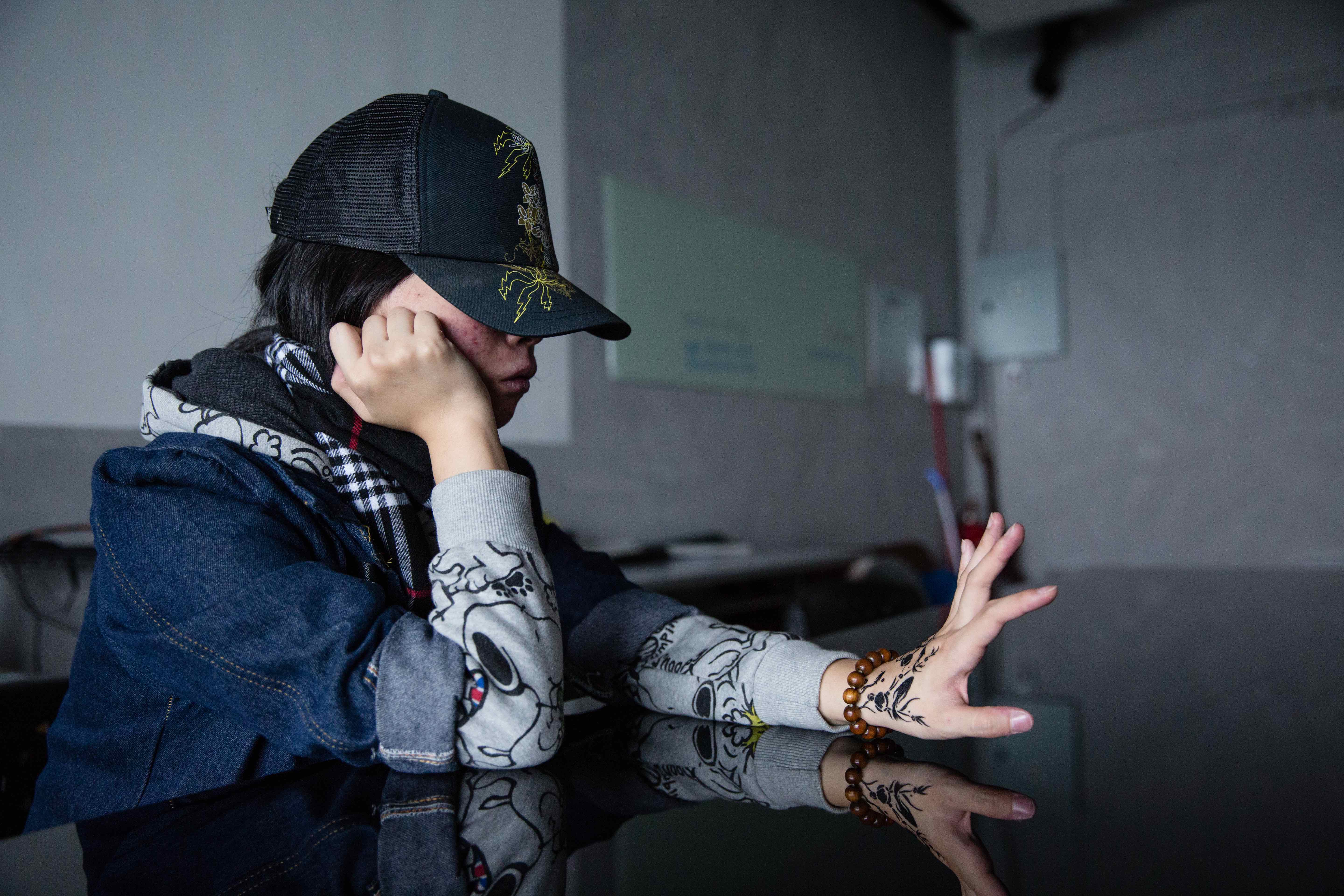 Tung, a recovering hikikomori, stares at a drawing of a fish on her hand.