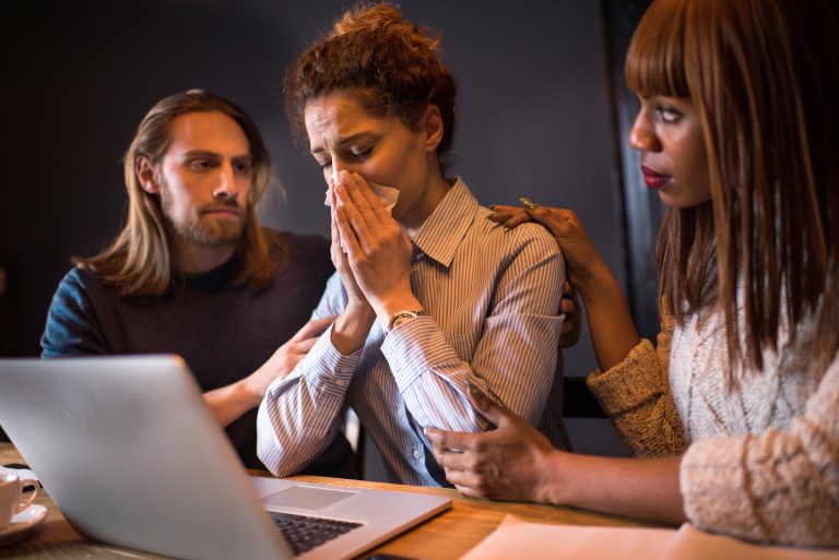 Drie geëmotioneerden achter laptop