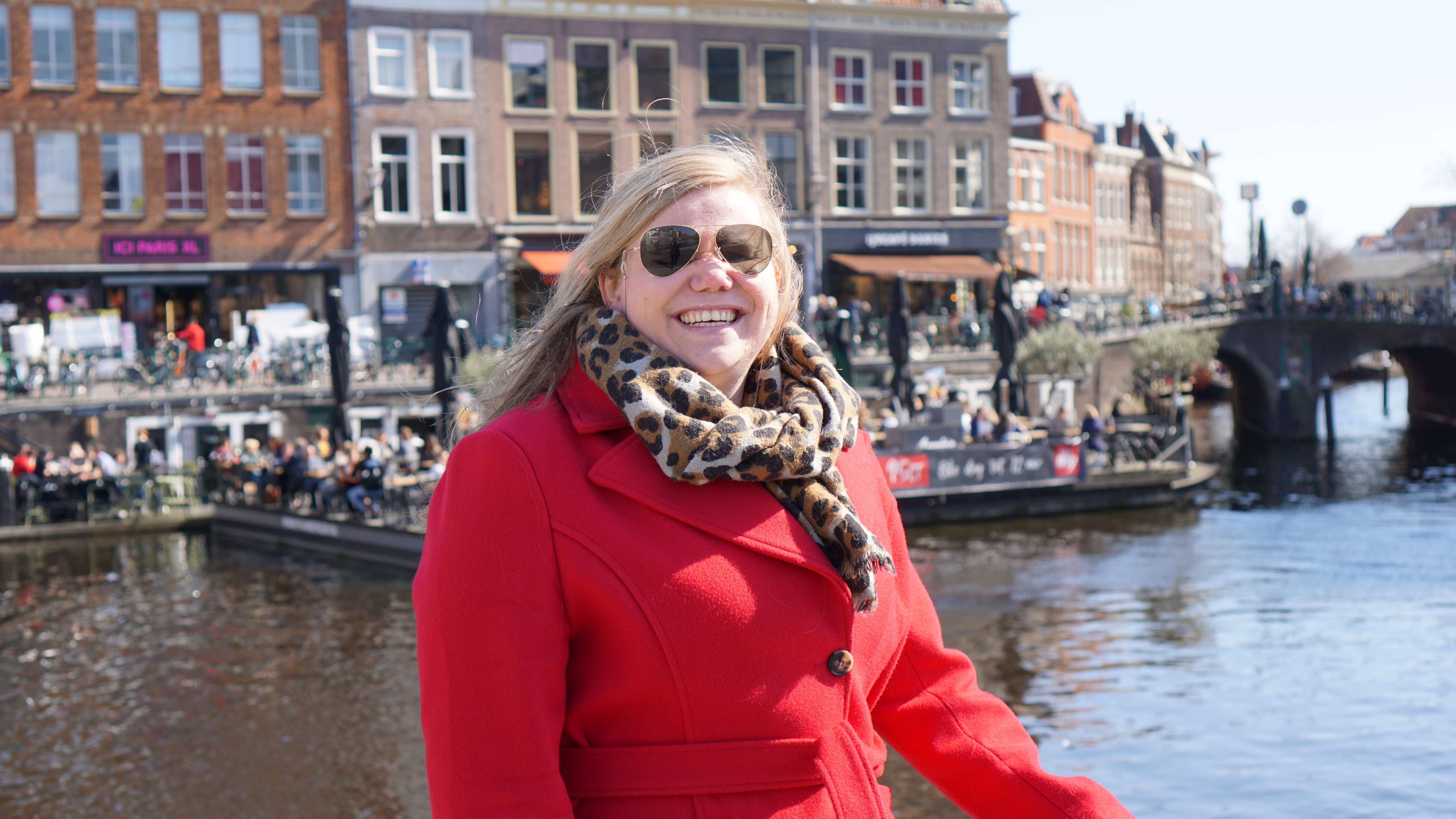 Vrouw met rode jas, tijgerprint sjaal en piloten zonnebril