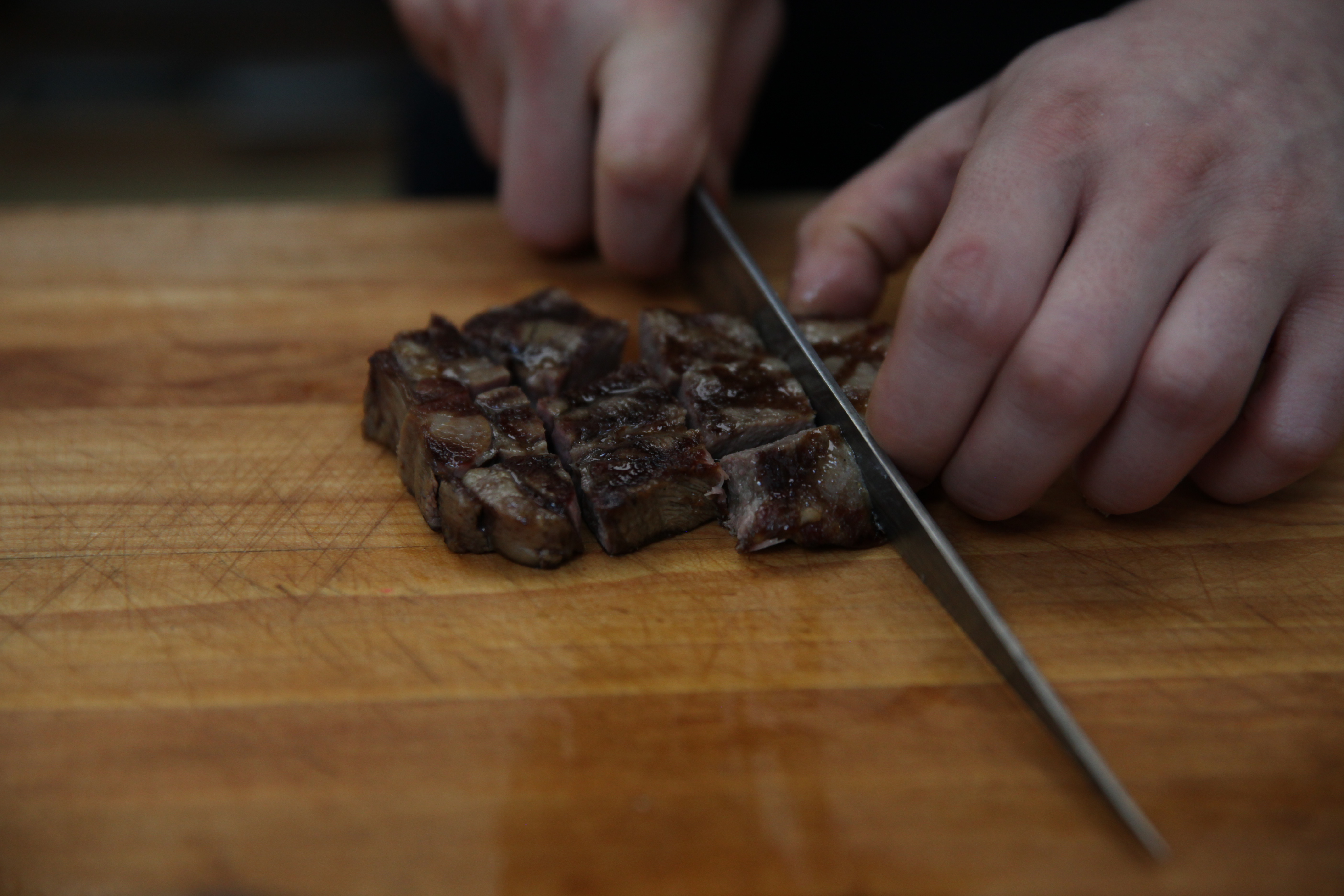 chef ed szymanski cutting grilled beef tongue into chunks