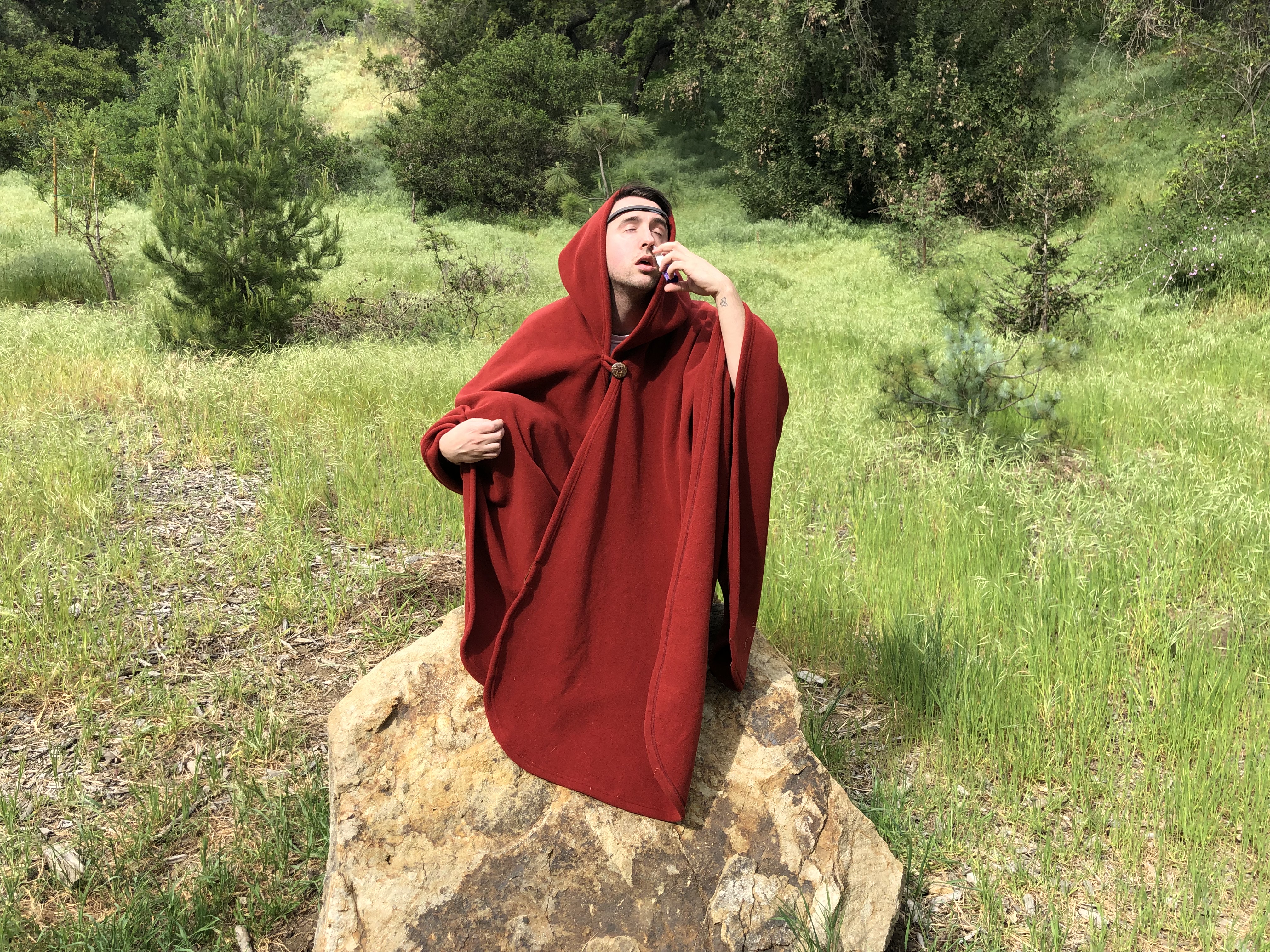 The author crouching on a rock in a red cape