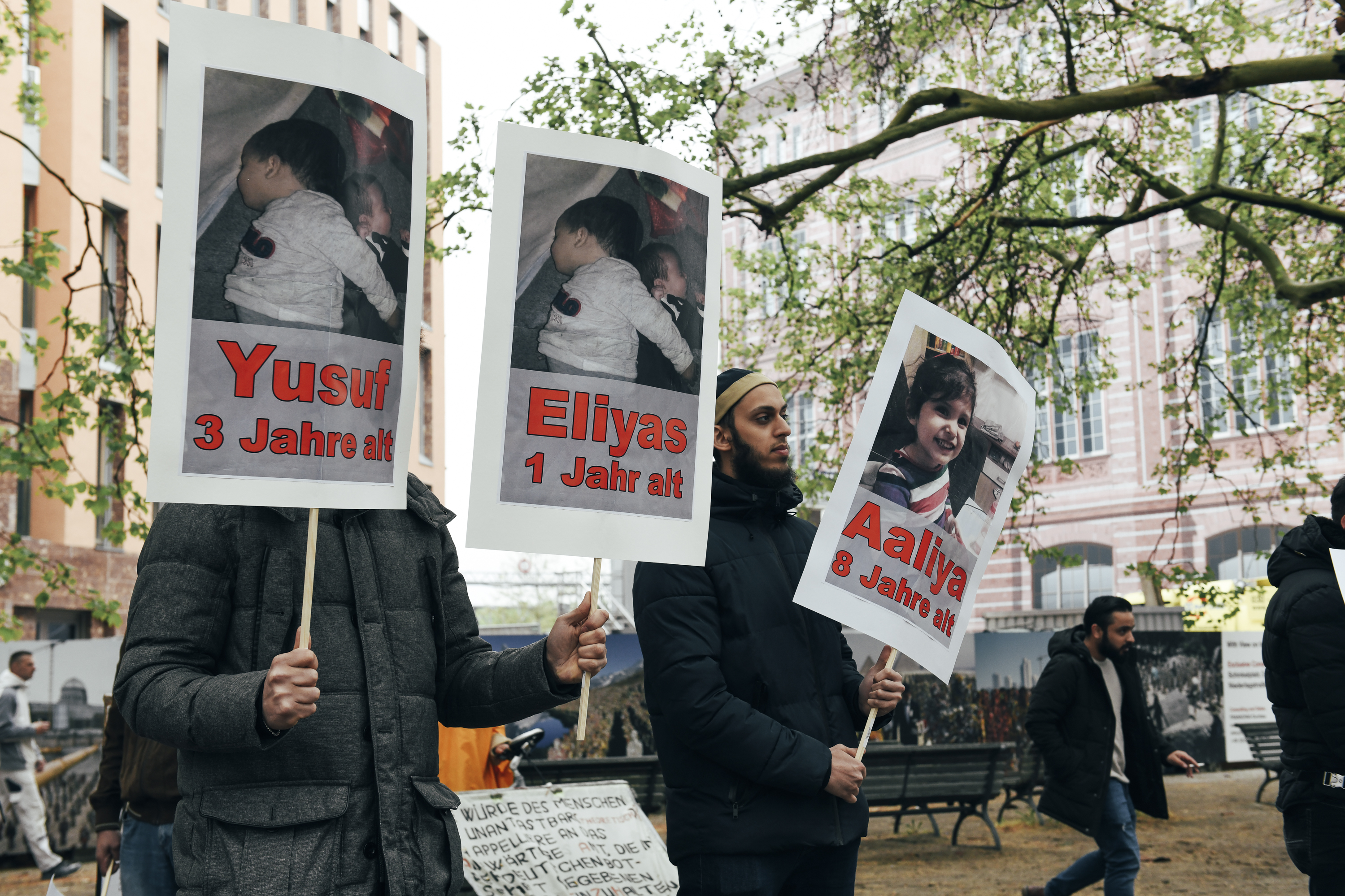 Demonstranten halten Schilder mit Kinderfotos hoch