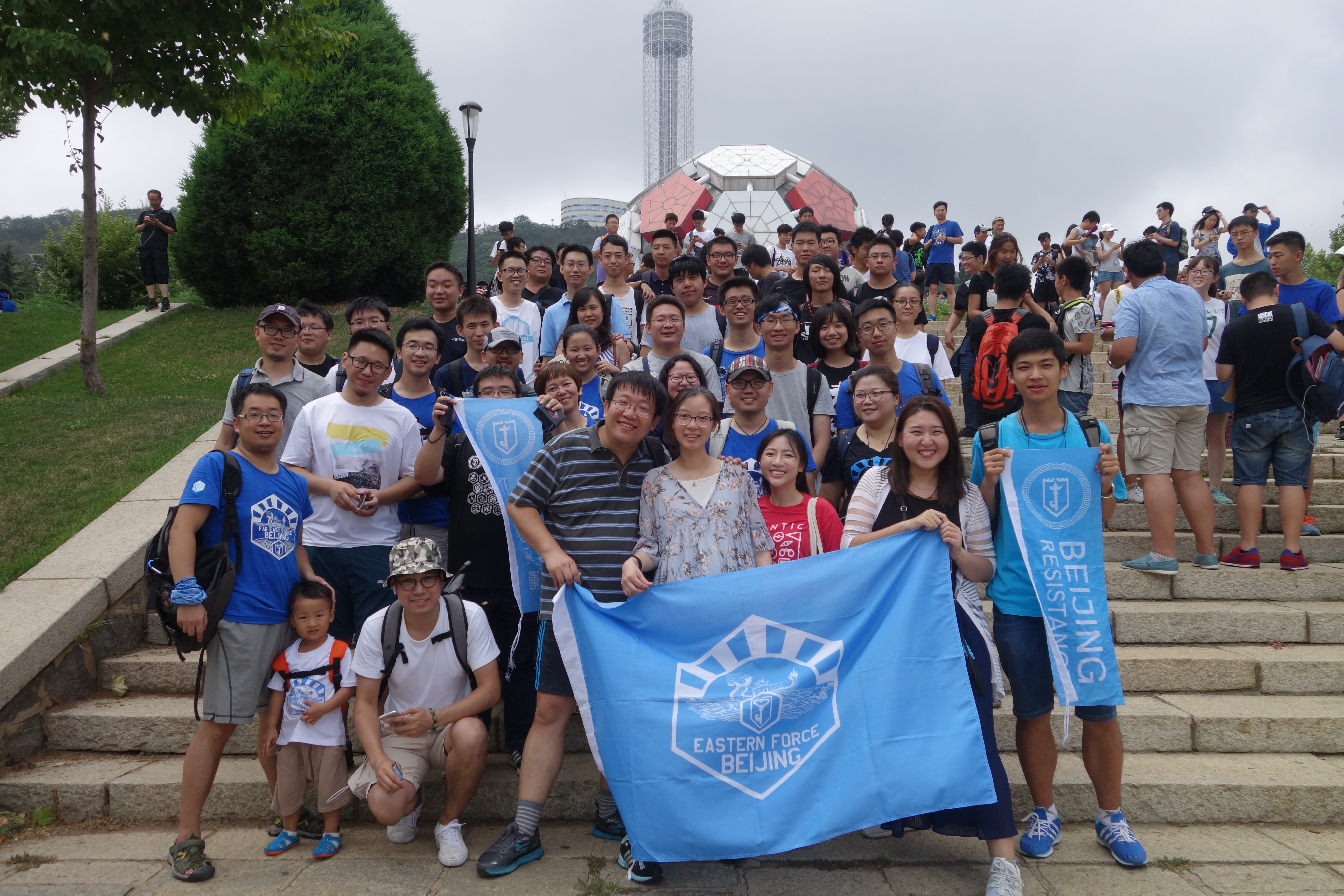 A group of Ingress players meet in a park, carrying a flag.