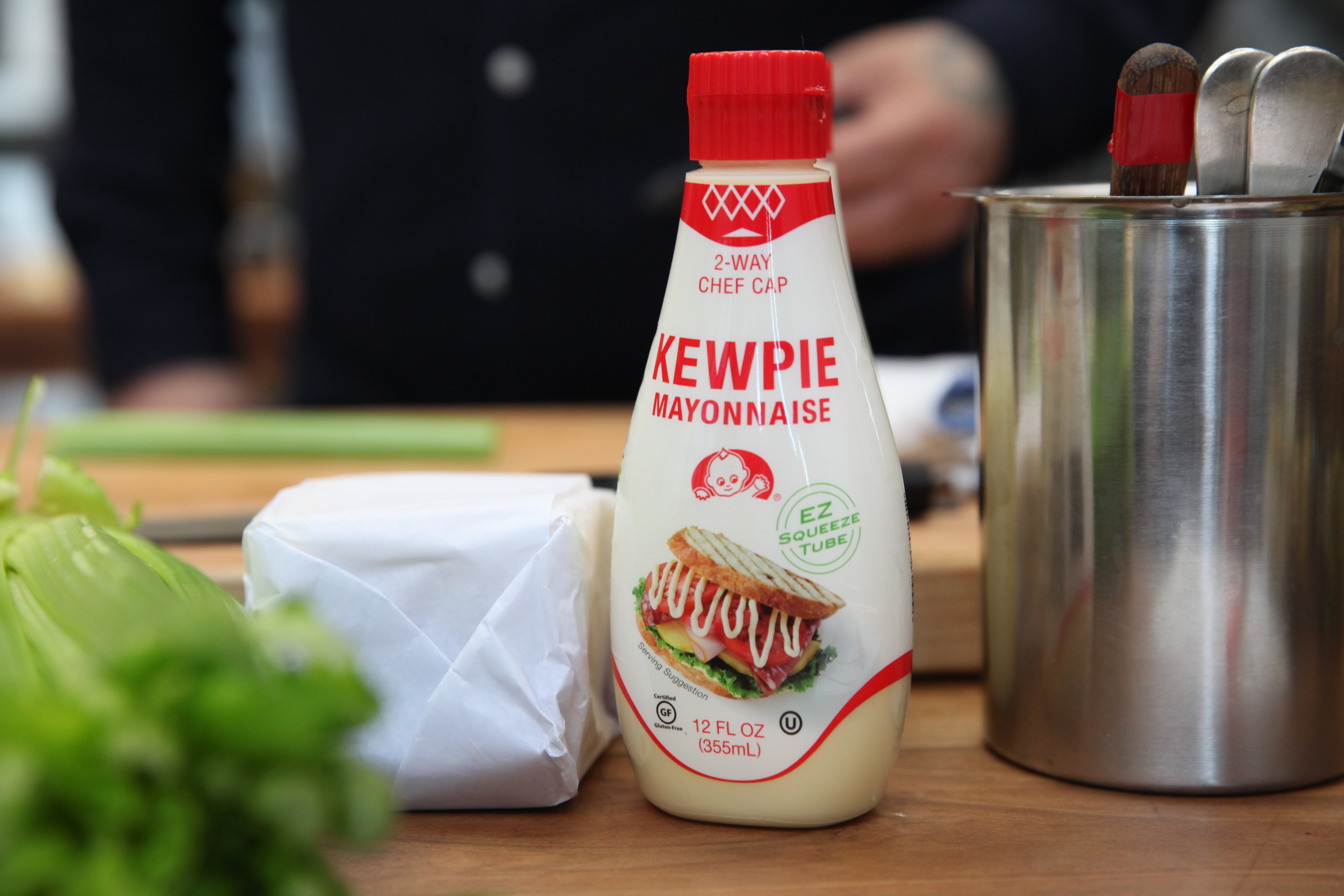 a squeeze bottle of japanese kewpie mayonnaise next to a paper-wrapped block of cheddar cheese