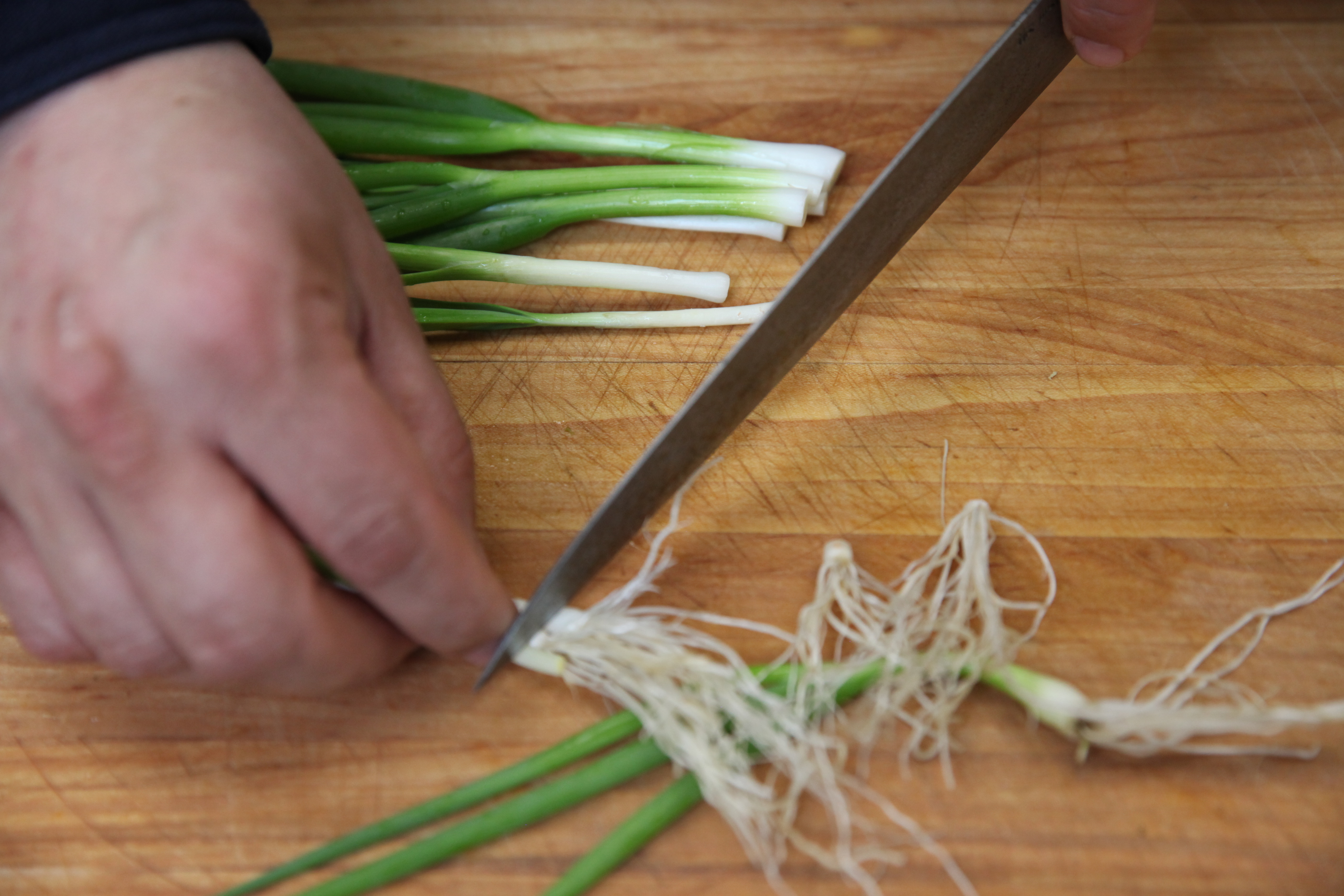chef erik anderson of coi slicing small green onions