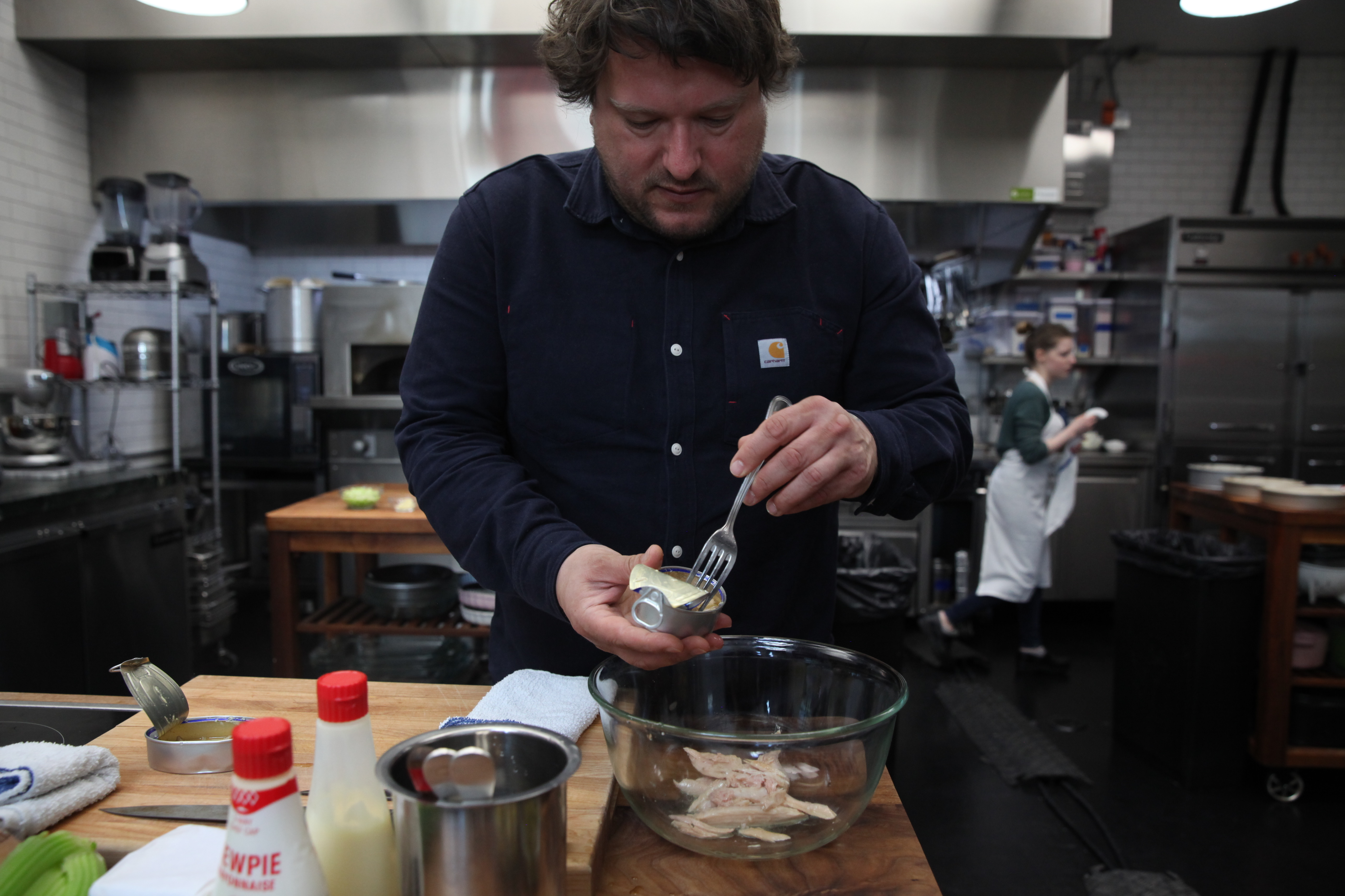 chef erik anderson of san francisco's coi opening cans of ventresca tuna into a bowl