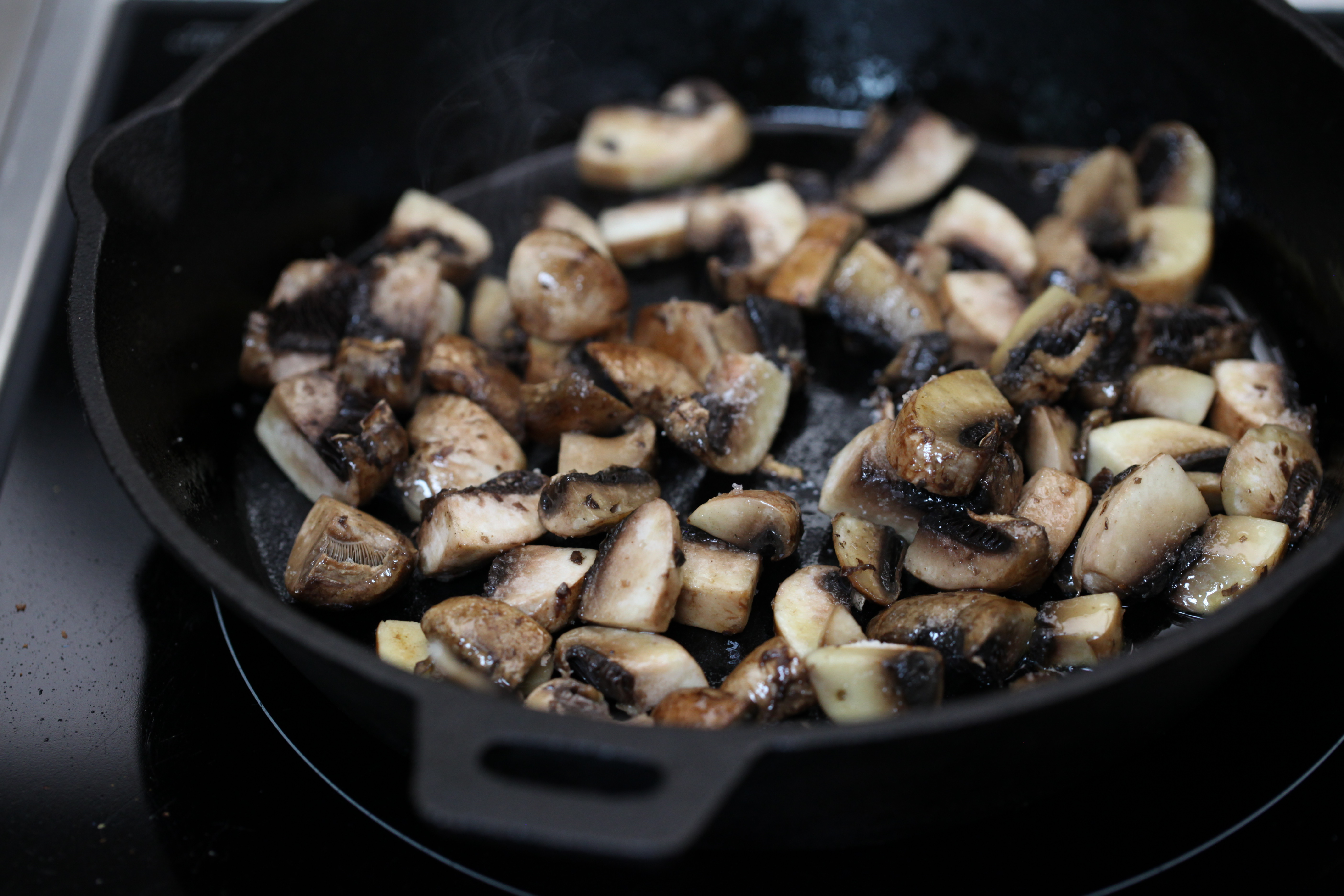 mushrooms cooking in a cast iron pan