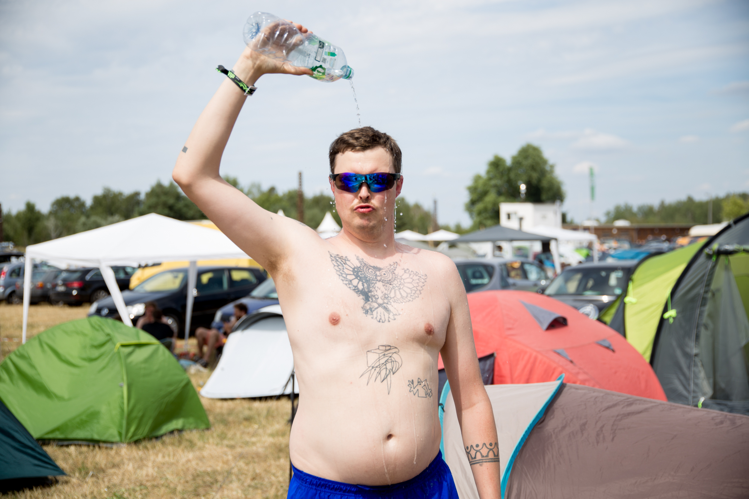Ein Mann auf einem Festival schüttet sich Wasser über seinen nackten Oberkörper