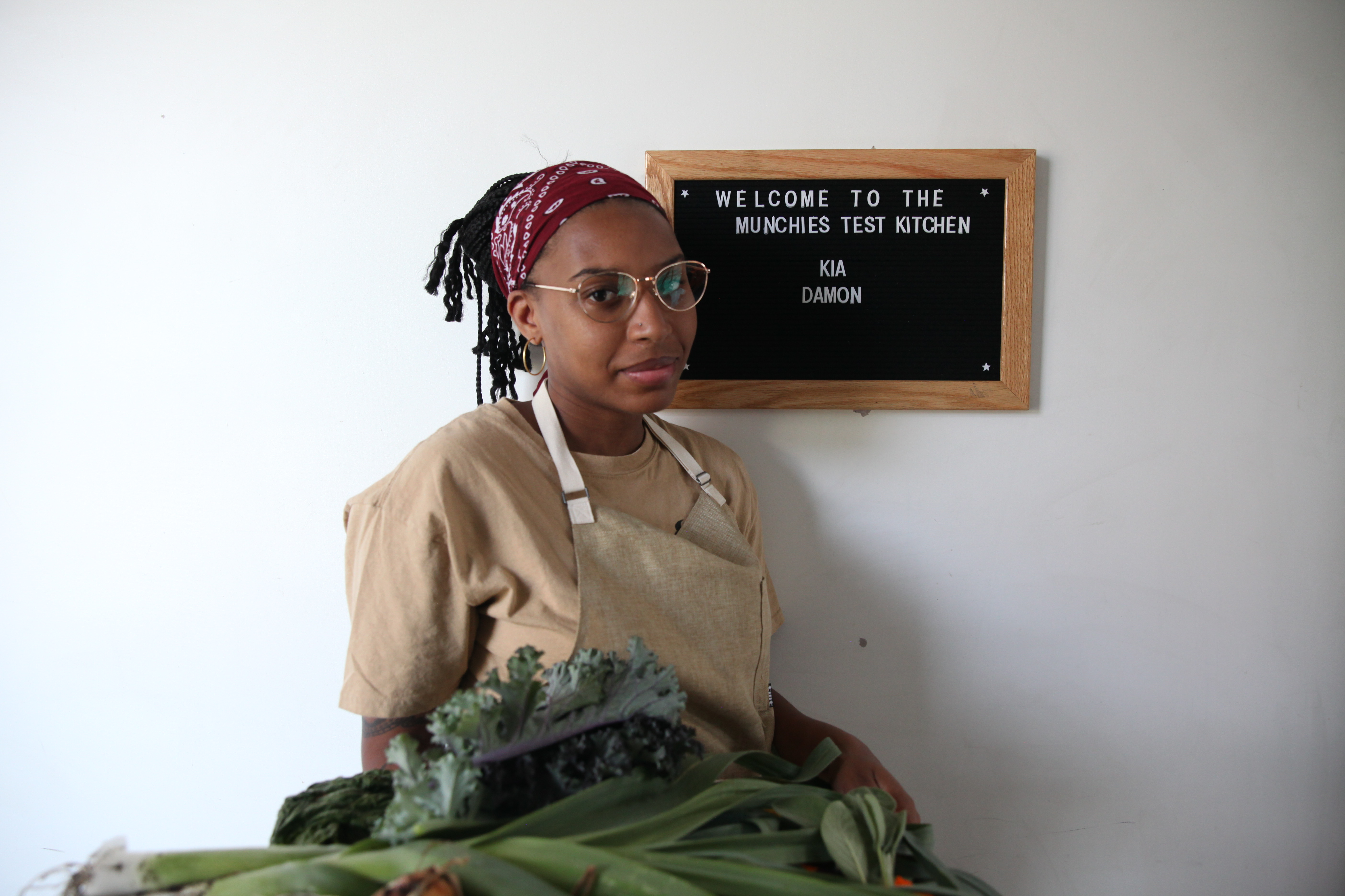 chef kia damon in the munchies test kitchen, holding a tray of freshly picked vegetables