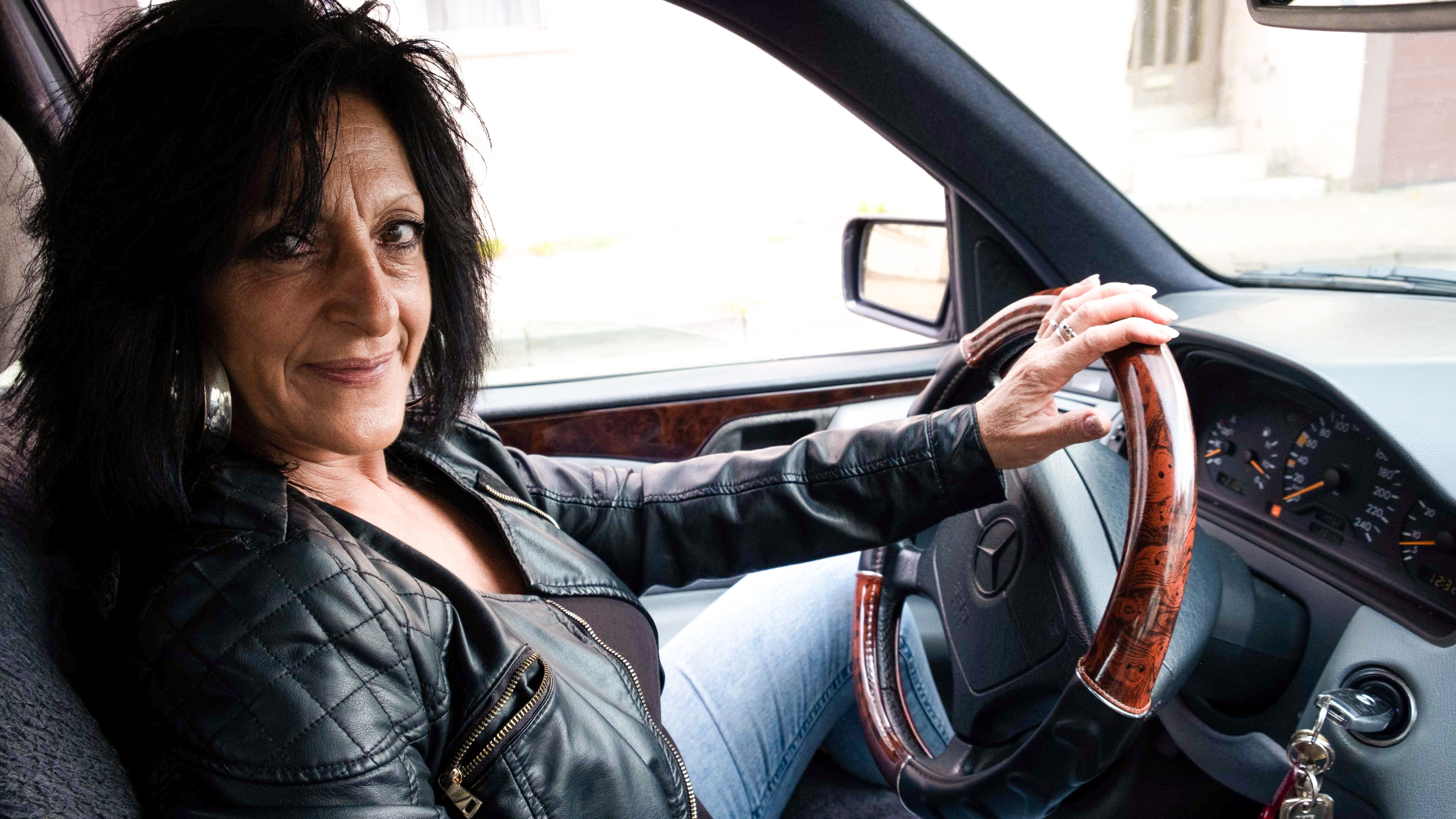 Die Taxifahrerin Vera Leidinger sitzt am Steuer und schaut in die Kamera