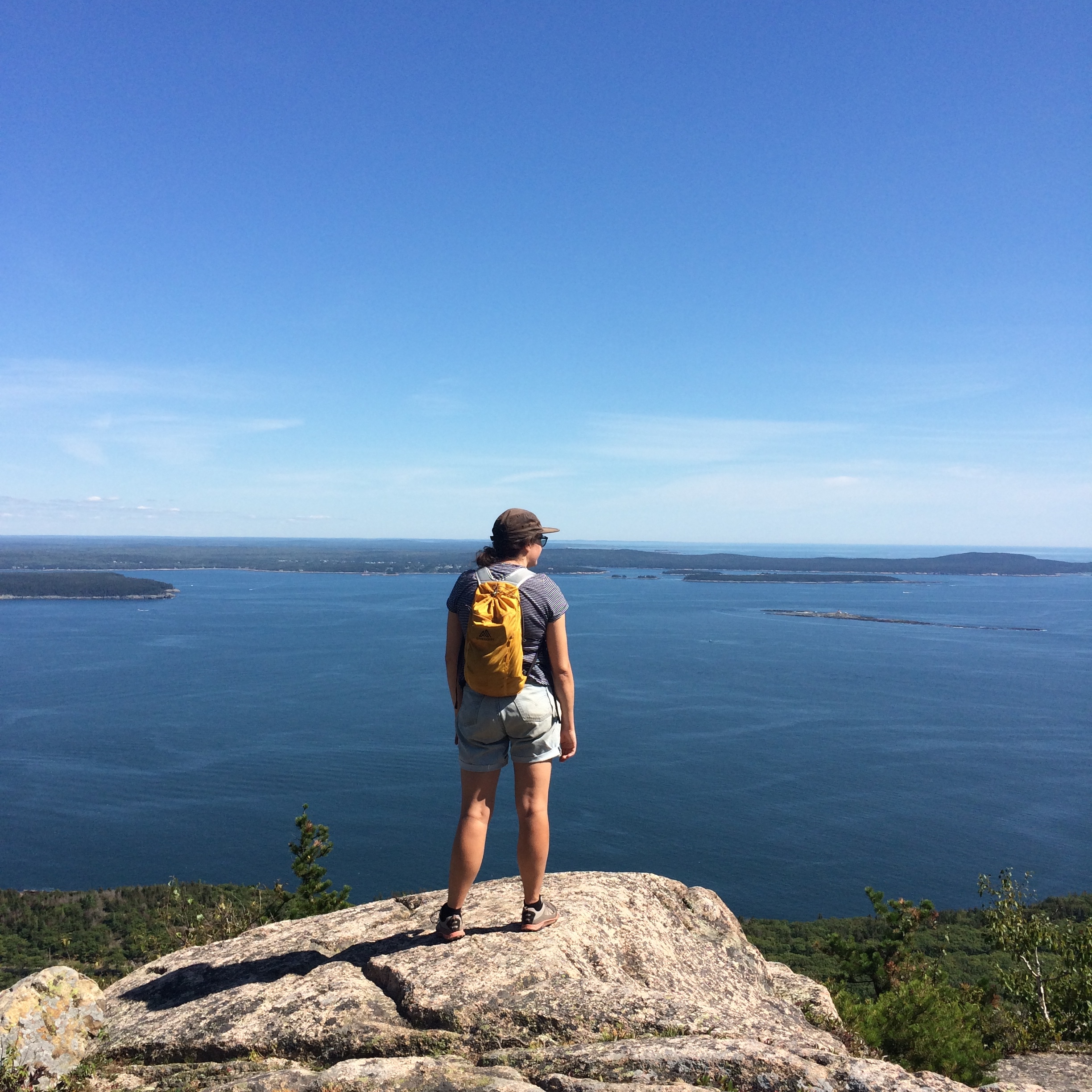 A vanlife adherent looking out onto the water with her backpack