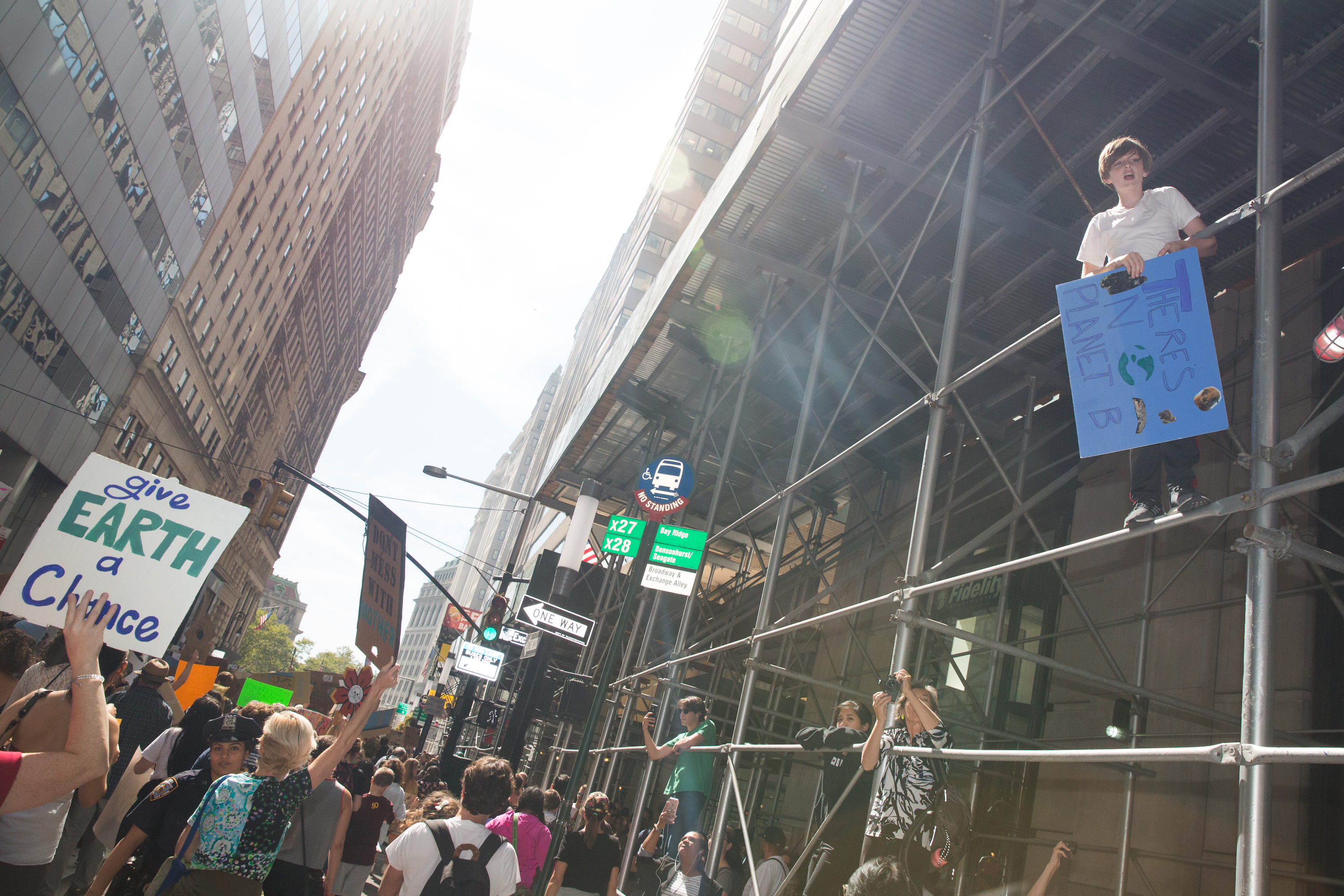 A young climate protester climbs some scaffolding above a crowd.