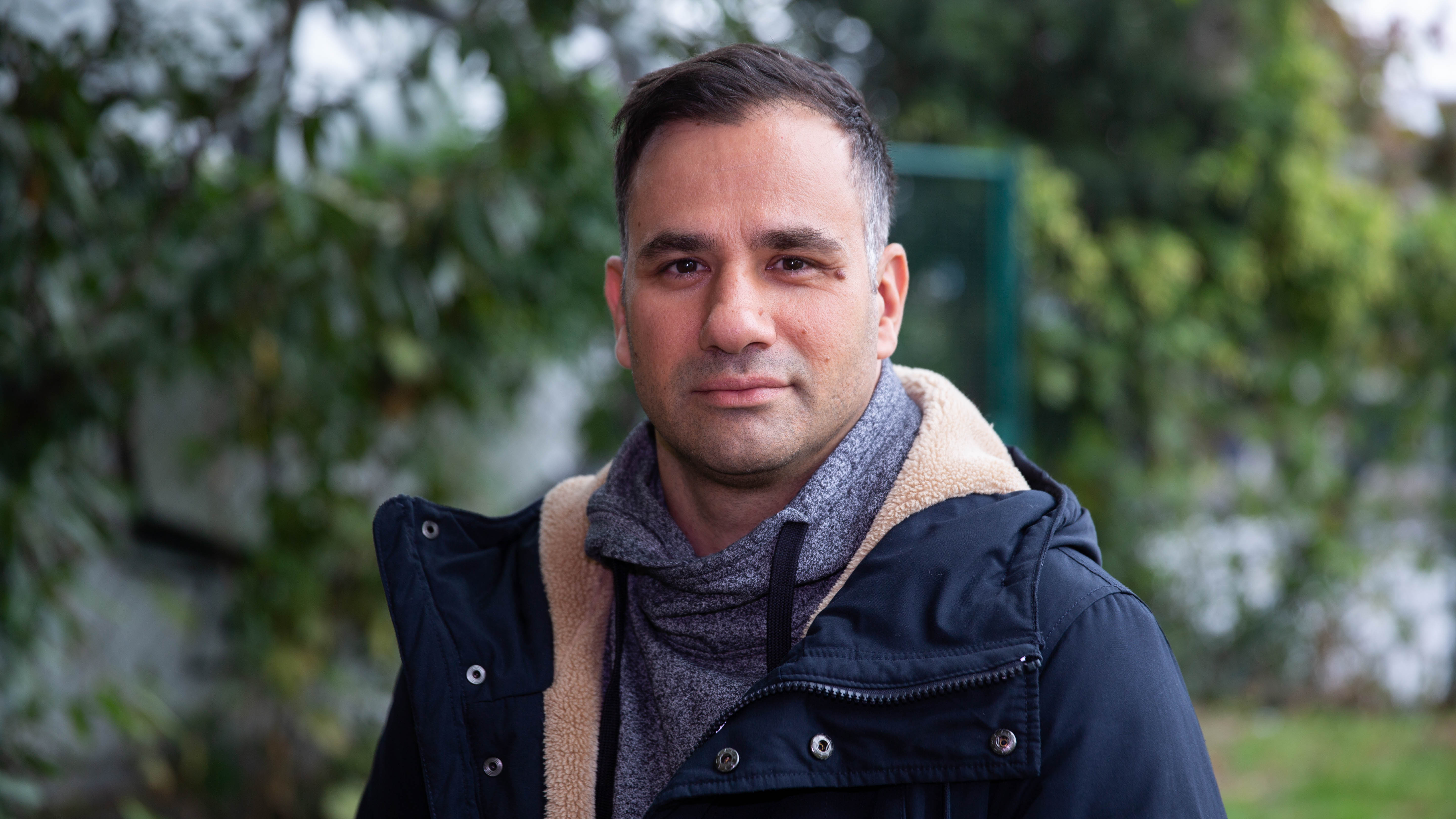 Mann mit dunklen Haaren, mittleren Alters, steht draußen, Portrait, leichtes Lächeln