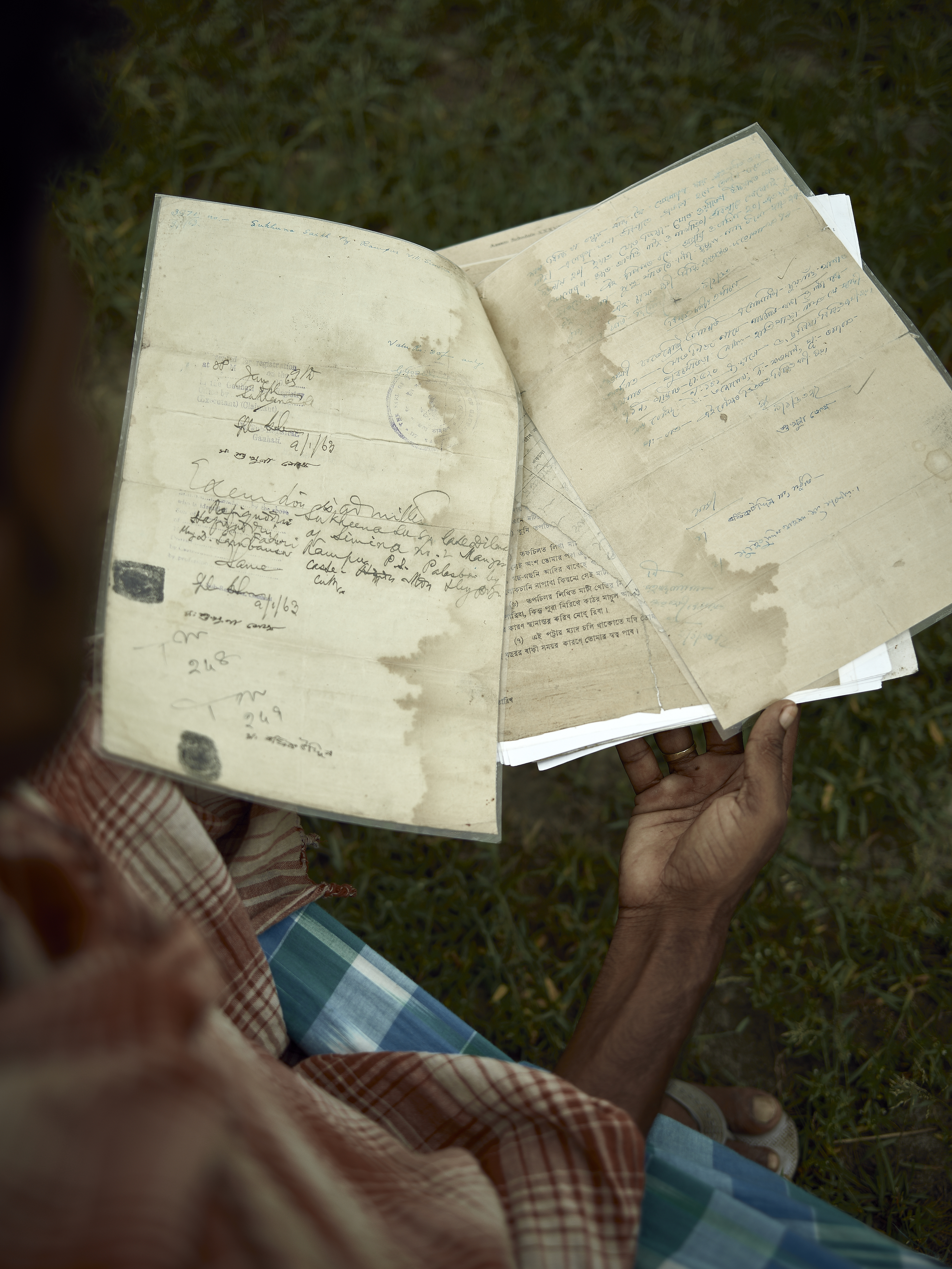 Land patta (land deed) documents, often decades old and damaged from floodwater, are crucial to NRC verification process.